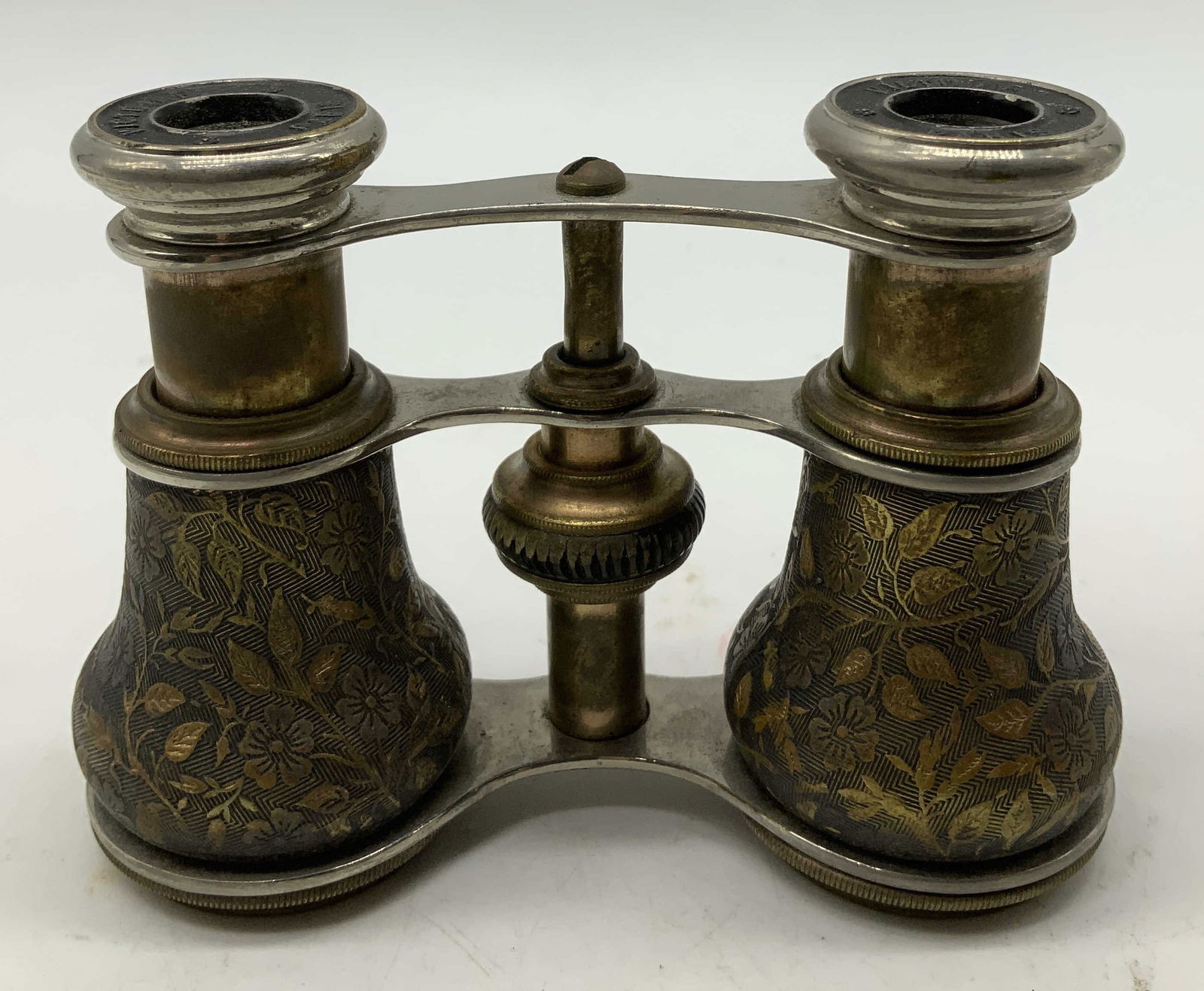 Antique Victoire Paris Brass Floral Opera Glasses: Antique pair of French opera glasses featuring ornate floral motifs on the barrels. Brass & silver toned accents. Sold as is. Signed & marked. Reads, VICTOIRE PARIS. Surface wear consistent to age, us