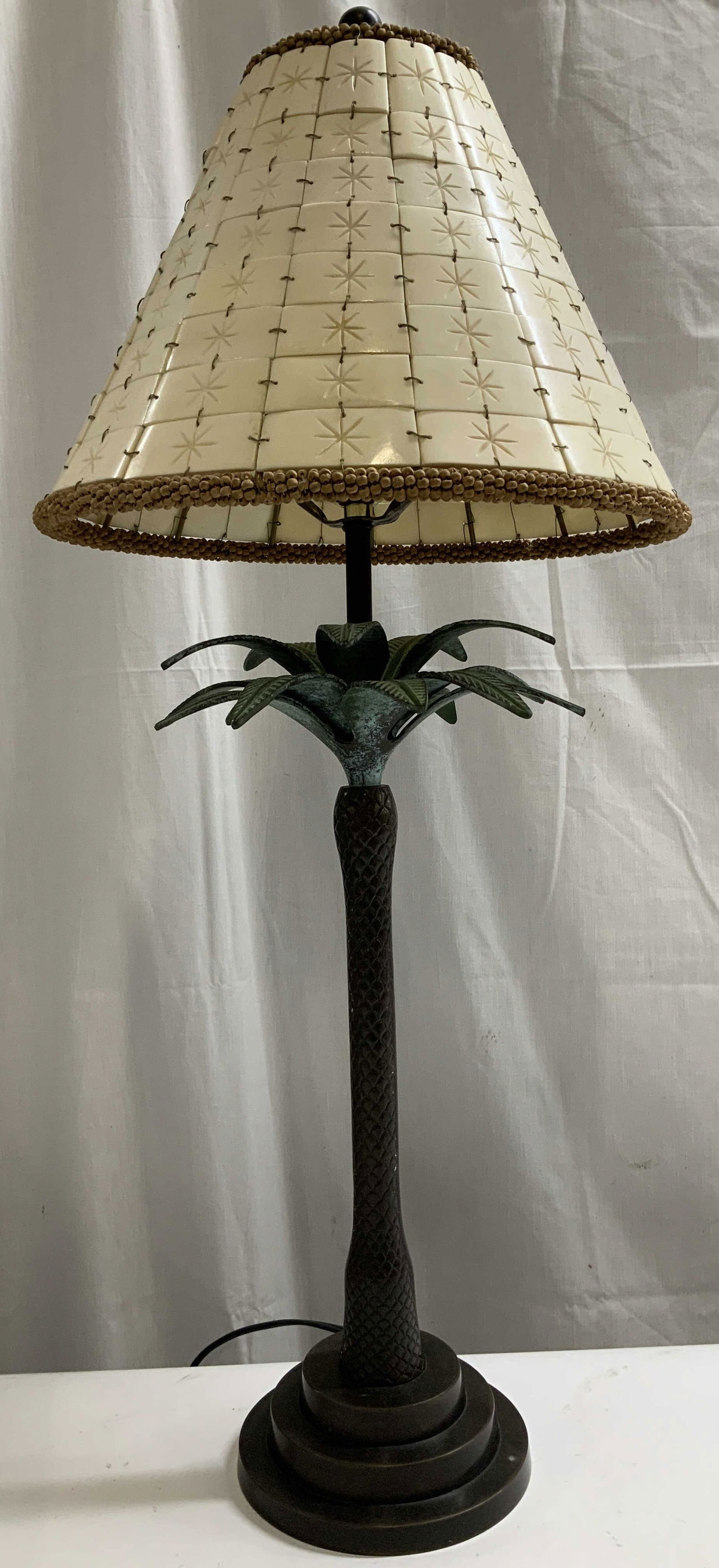 Vtg Bronze Palm Tree Table Lamp 28.2in: Vintage palm tree table lamp features a bronze base, textured palm tree trunk with detailed green leaf accents. Shade features a beaded finish & faux bone accents. Sold as is. Table lamp has not been