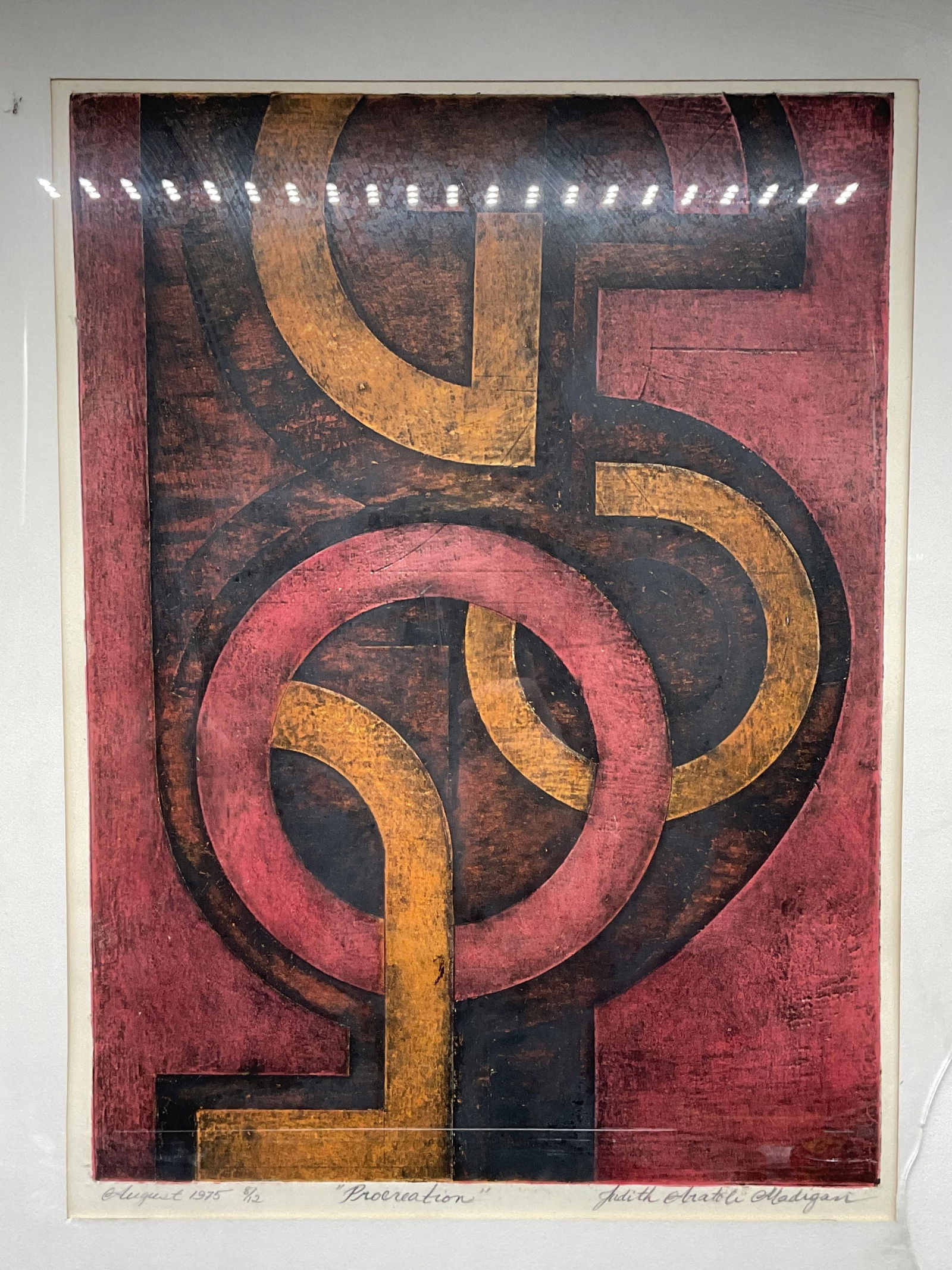 Signed Judith Madigan Abstract Ltd Edt Etching 21i: Framed and matted color etching. Signed, titled, and numbered along margin, Judith Aratoli Madigan, Procreation, 1975, 8/12. Abstract geometric composition in red, orange, and black. Gold tone metal f