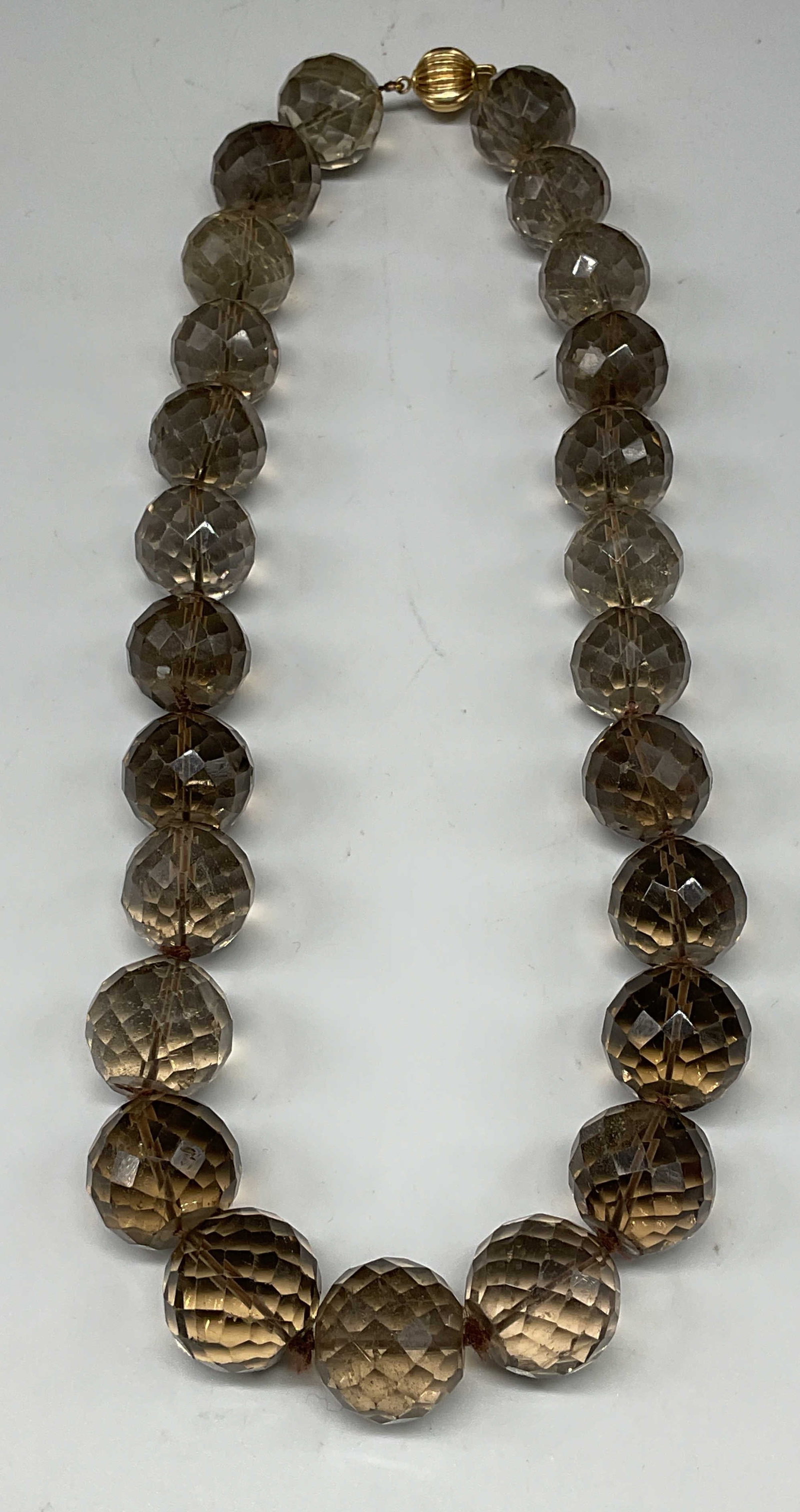 Vtg 14k Gold Semiprecious Beaded Necklace: Vintage Smokey semiprecious faceted gemstone beaded necklace with 14k gold clasp. Marked 14k. Additional mark illegible. Drop length approx 8.5 inches. Total weight 182.1 grams. Some scratching. Jewel