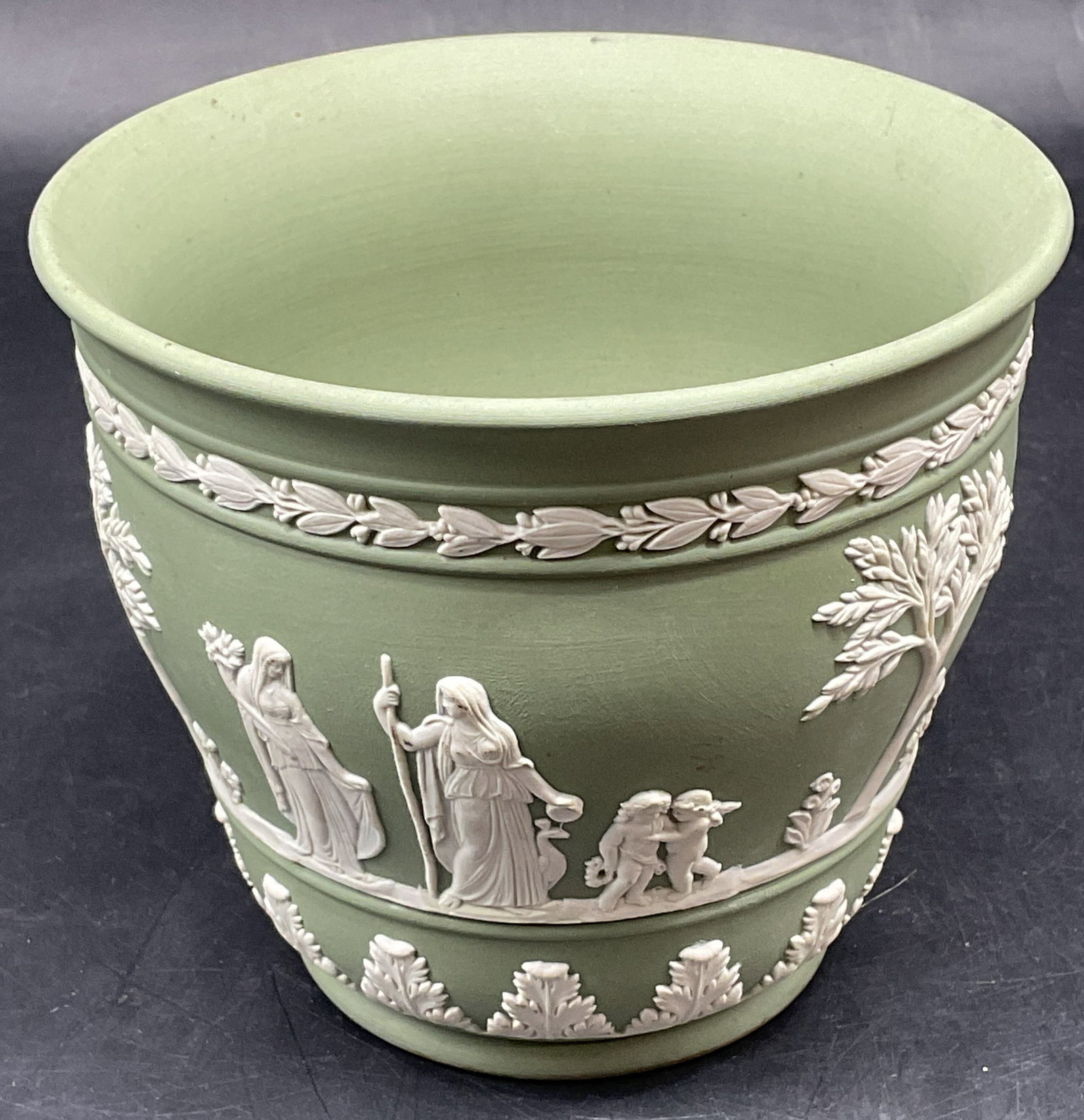 Wedgwood Green Jasperware Planter England: Vintage Wedgwood green Jasperware planter. White bas relief with classical figure and botanical motifs. Signed. Made in England. Measures approx. measures approx. 5 x 4.25 inches. Some scratching. Wed