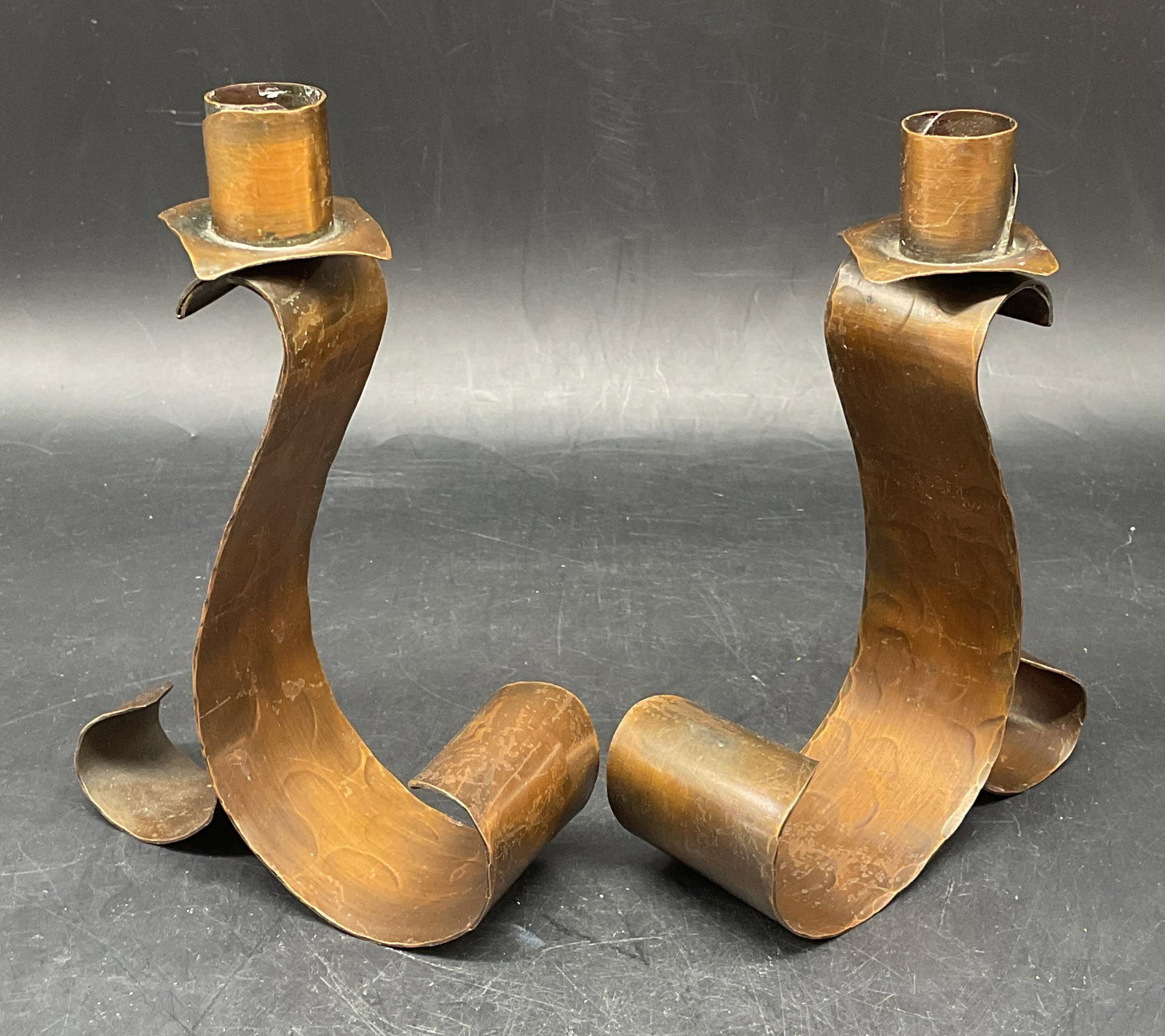 Near Pair Vtg Hammered Copper Candlesticks: Near pair of vintage hammered copper curved candlesticks. Taller measures approx. 4.75 x 2 x 6.75 inches. Wear including scratching, patina, some warping. Copper candlesticks, Vintage candlesticks, ho