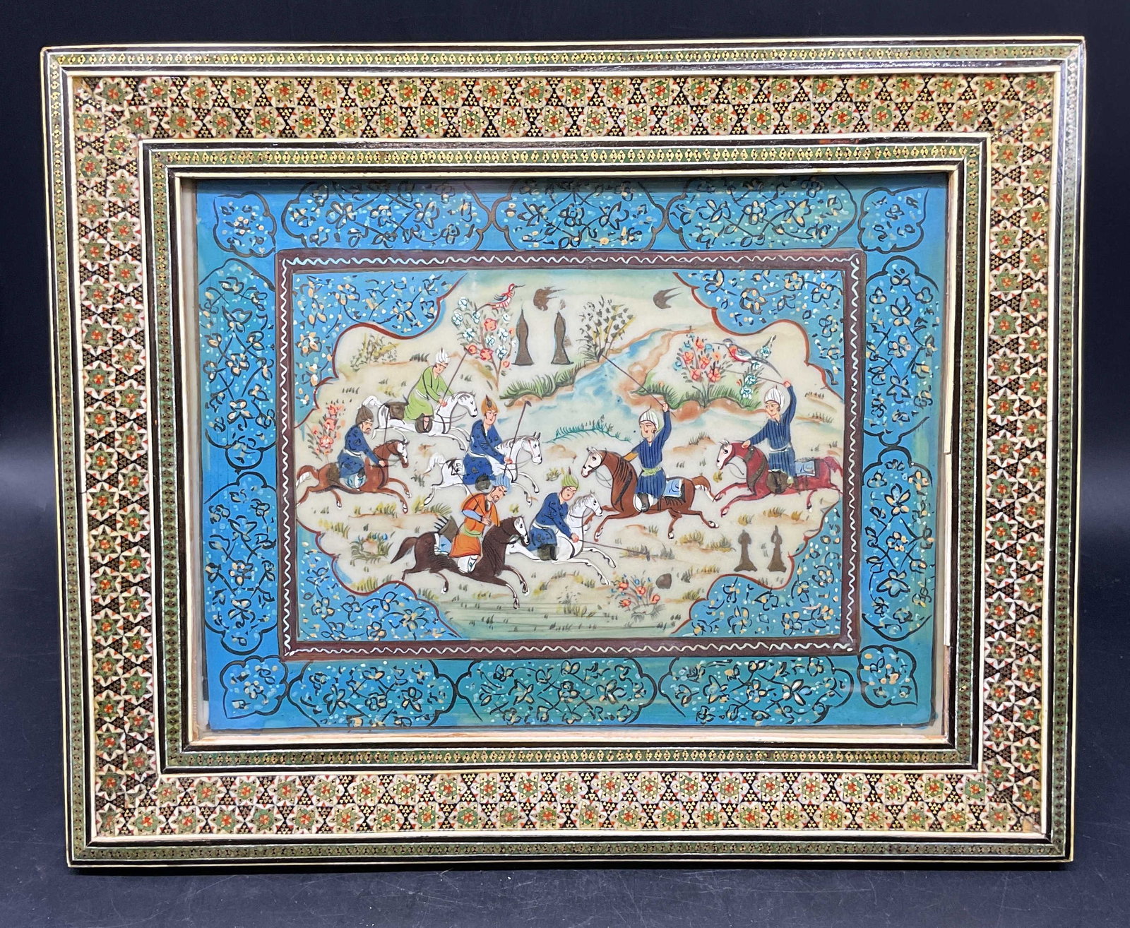 Framed Persian Miniature Polo Scene Painting: Framed Persian miniature painting. Polo scene, men on horseback. Khatam Kari inlaid wood and bone geometric motif frame. Not examined out of frame. Frame measures approx. 10 x 12 inches. Some wear inc