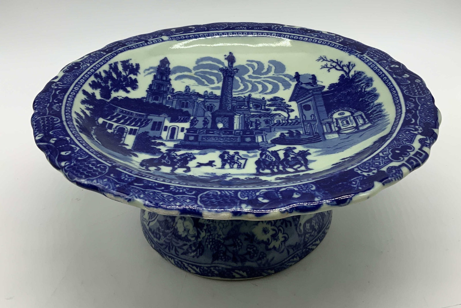 Vtg Victoria Ware Ironstone Footed Compote: Vintage Victoria Ware footed compote features a blue & white transferware pattern. Horse, figures & building motifs. Ironstone material. Signed & marked on underside. Reads, VICTORIA WARE IRONSTONE. S