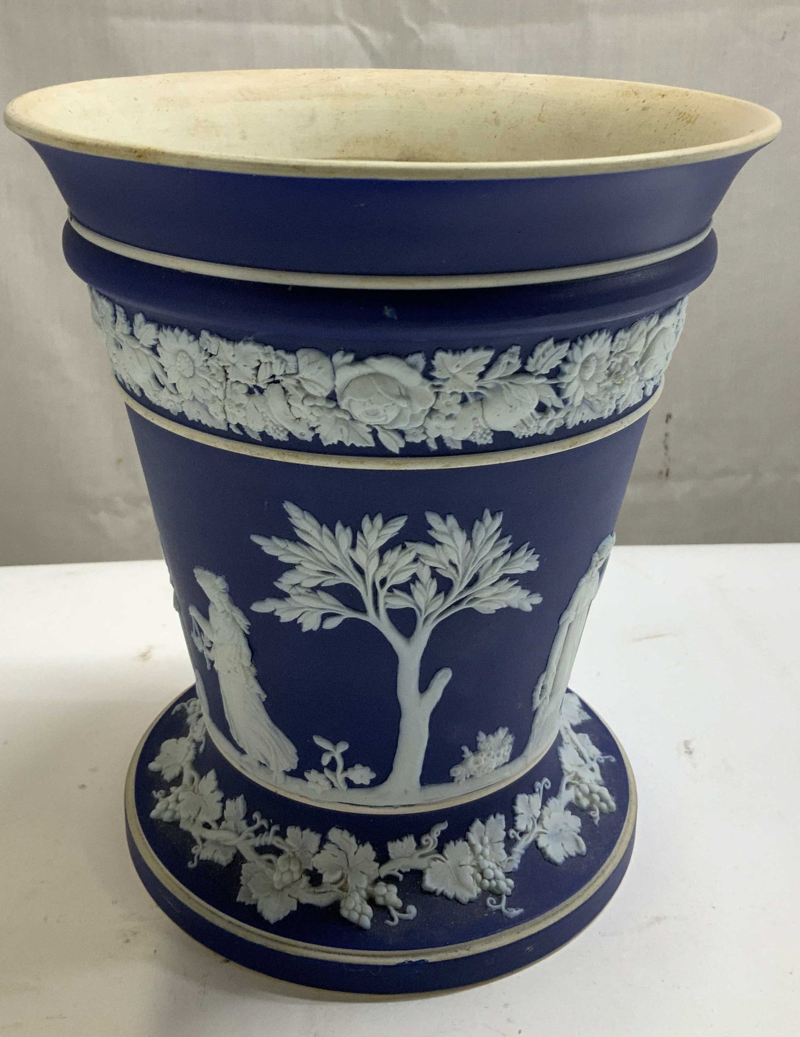 Vtg Wedgwood Blue Jasperware Vase ENGLAND: Vintage Wedgwood Jasperware vase featuring neoclassical white relief figures of Greek women, cherubs & trees. Dark matte blue finish. Signed & marked on underside. Reads, WEDGWOOD MADE IN ENGLAND. Sur