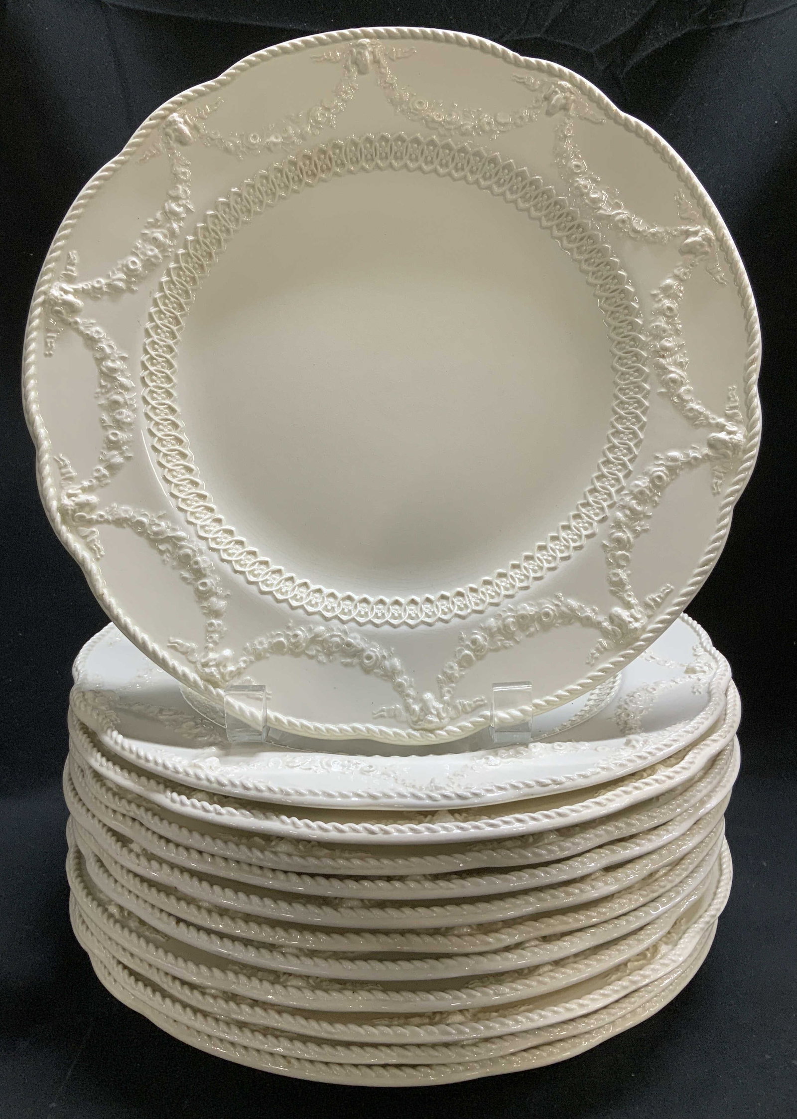 Lot 12 Vtg Wedgwood Etruria Embossed Plates ENG: Lot includes, 12 vintage Wedgwood Etruria dinner plates featuring embossed floral swags. Scalloped rim. Ceramic material. White toned. Signed & marked on underside. Reads, WEDGWOOD ETRURIA ENGLAND. Su