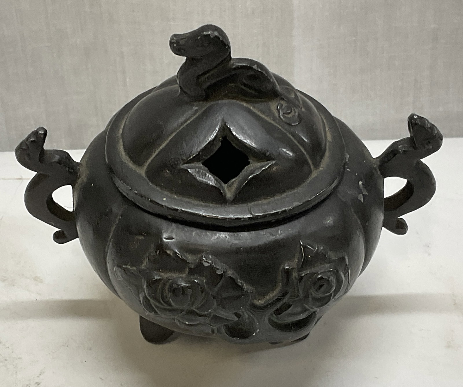 AMW Asian-Style Metal Incense Burner: AMW Asian-Style Metal Incense Burner. Made by AMW Newark, NJ. Metal with a bronze toned patina. Lidded with twin handles. Sits on 3 feet. Features mythical creature motifs. Condition consistent with e