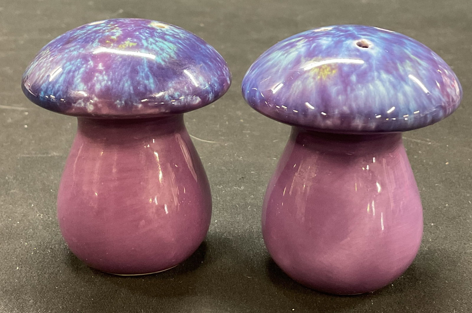 Vtg Ceramic Mushroom Salt & Pepper Shakers: Vintage purple ceramic mushroom salt and pepper shakers. Mushroom shape. Wide round top, bulbous stem. Purple and blue abstract pattern, hand painted. Glossy finish. Measures ht approx 3 inches diam a