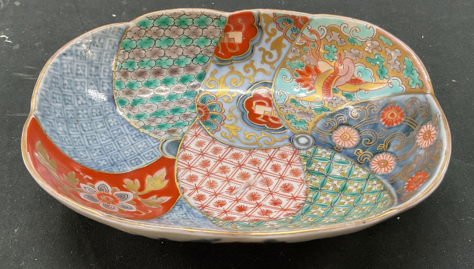 Vtg Japanese Porcelain Imari Trinket Dish: Vintage Japanese porcelain Imari trinket dish. No visible markings. Scalloped edge with gilt rim. Hand painted bird, floral, and geometric motifs. Blues, reds, greens, etc. Gilt accents. Measures appr