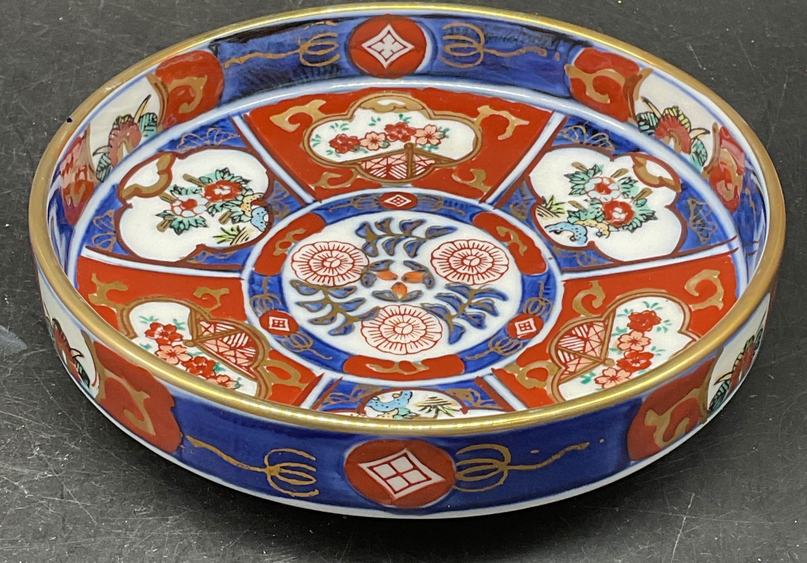 Gold Imari Blue Red Porcelain Floral Bowl Japan: Signed Gold Imari porcelain Imari pattern bowl. Iron red and cobalt blue with gilt decoration. Hand painted. Made in Japan. Measures approx. 5.25 x 1.5 inches. Some scratching and loss to paint. Gold