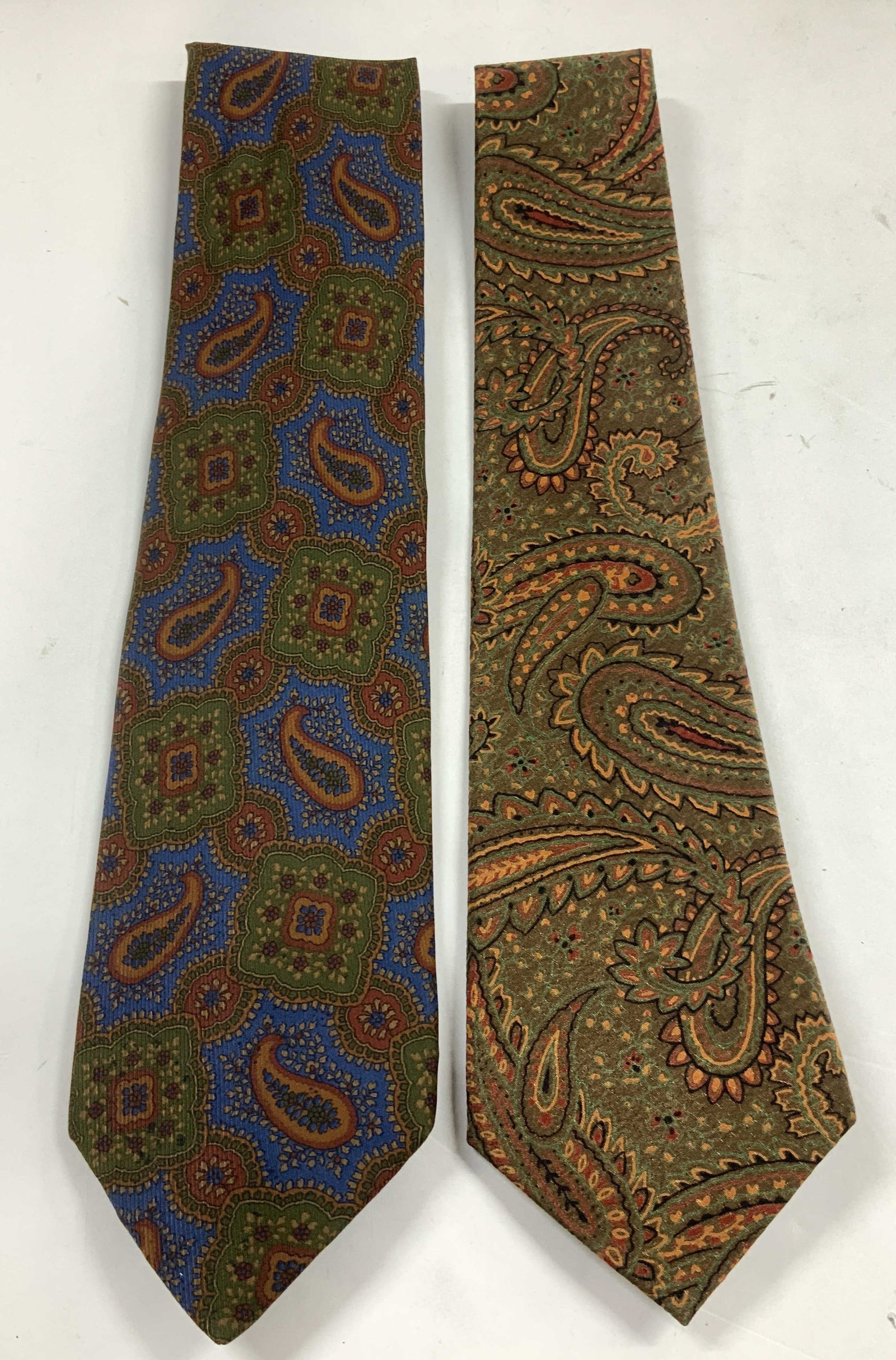 Lot 2 Vtg Paisley Silk Neckties CALYPSO+: Lot includes, 2 neckties featuring paisley patterns. Shades of green, red, orange, black, blue, brown. Silk material. Assorted sizes. Sold as is. Signed & marked. Reads, CALYPSO HAND MADE. Surface wea