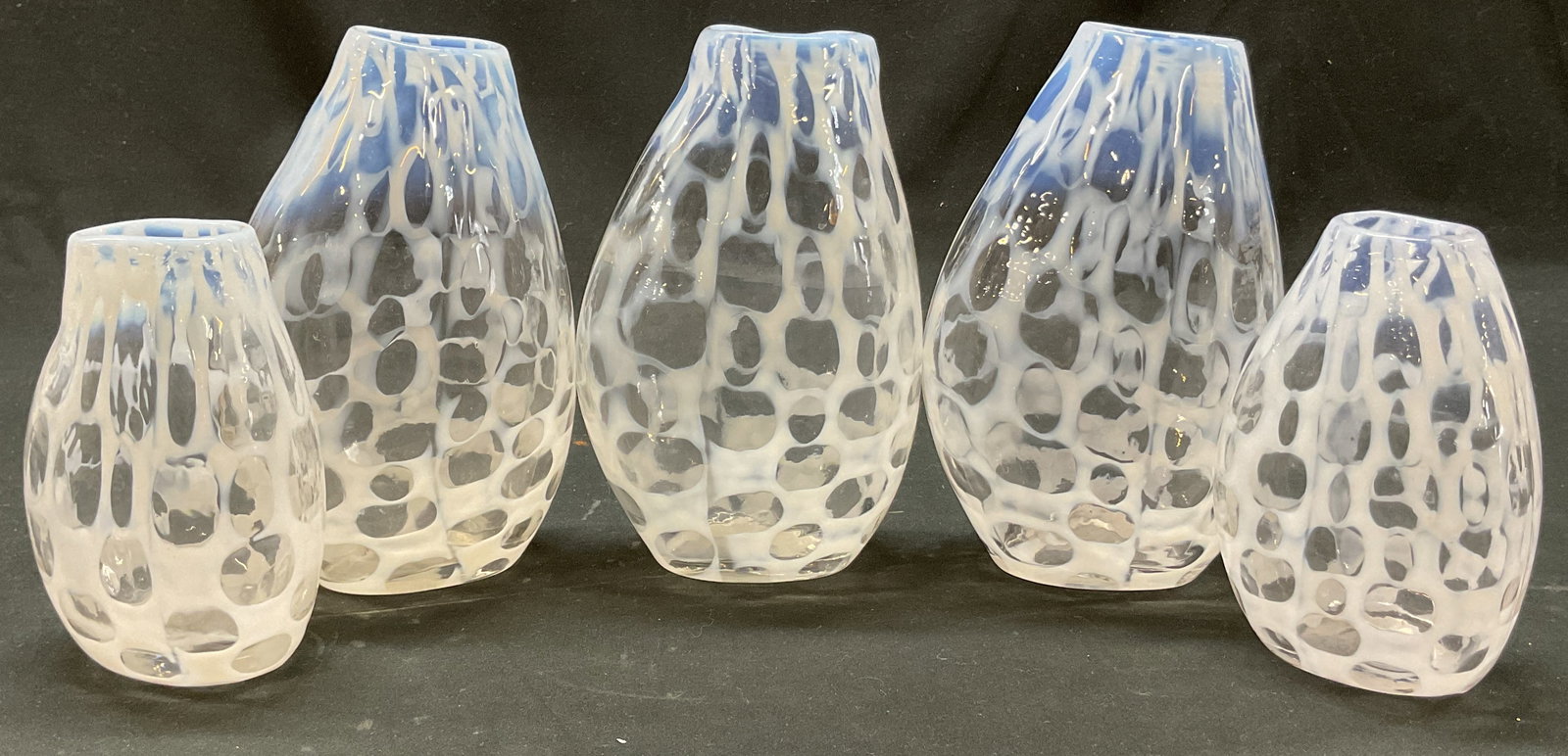 Set 5 Hand Blown White Art Glass Vases: Set of 5 hand blown white art glass vases. Geometric pattern in white. Curved shape. Sizes vary. Largest measures ht approx 6 inches base diam approx 2.5 inches. Surface wear consistent with exposure.