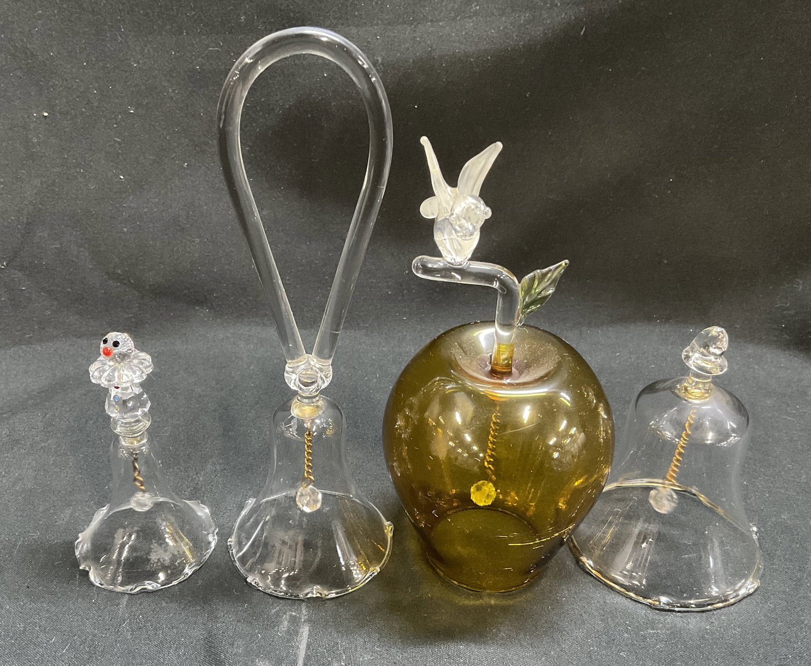 Lt 4 Glass Apple, Bird and Clown Bells: Lt 4 Glass Apple, Bird, and Clown Bells. Amber Colored Glass Apple Bell with Bird Perched, Bell with Loop Handle, Bell with Gold Toned Trim, and a Bell with a Crystal Clown on Top. Some chips such as