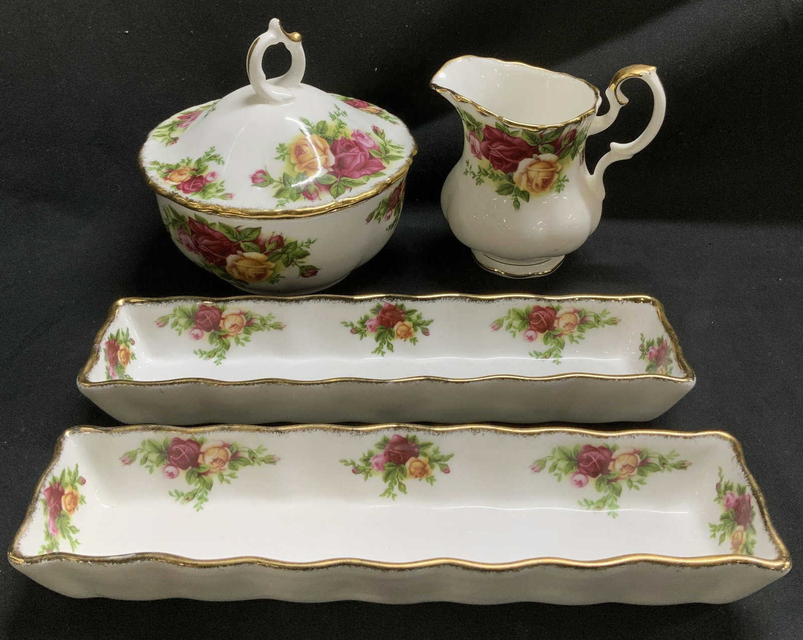 Set 4 1962 Royal Albert Trays, Creamer & Powder Bwl: Lot includes, 2 mint trays, 1 creamer & 1 lidded powder bowl. Pieces are fine china material & feature vibrant floral motifs. Gilt accents. Scalloped rim. Old Country Roses pattern. Surface wear consi