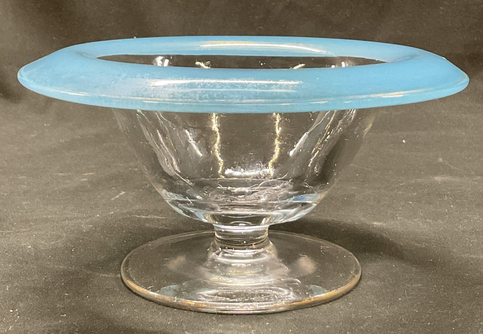 Vintage Blue Glass Footed Pedestal Bowl: Vintage blue glass footed pedestal bowl. Round base with short pedestal. Wide round bowl. Thick blue rim. Measures ht approx 3 inches diam approx 7 inches. Surface wear consistent with exposure. Bowl,