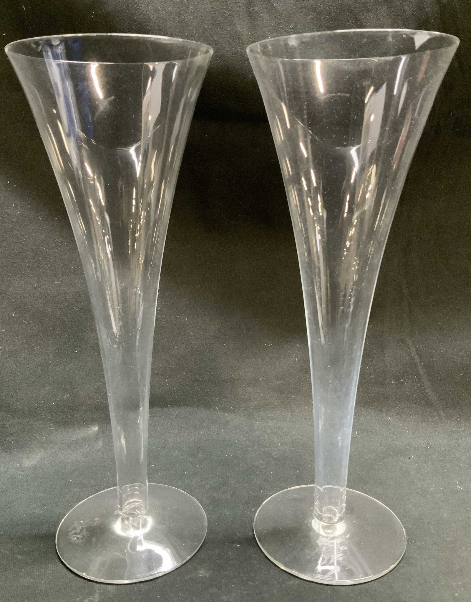Pair Tiffany & Co. Glass Champagne Flutes: Lot includes, a pair of Tiffany & Co. glass champagne flutes. Round base. Signed & marked on underside. Reads, TIFFANY & CO. Surface wear consistent to age, use & exposure. Measurements: length of bas