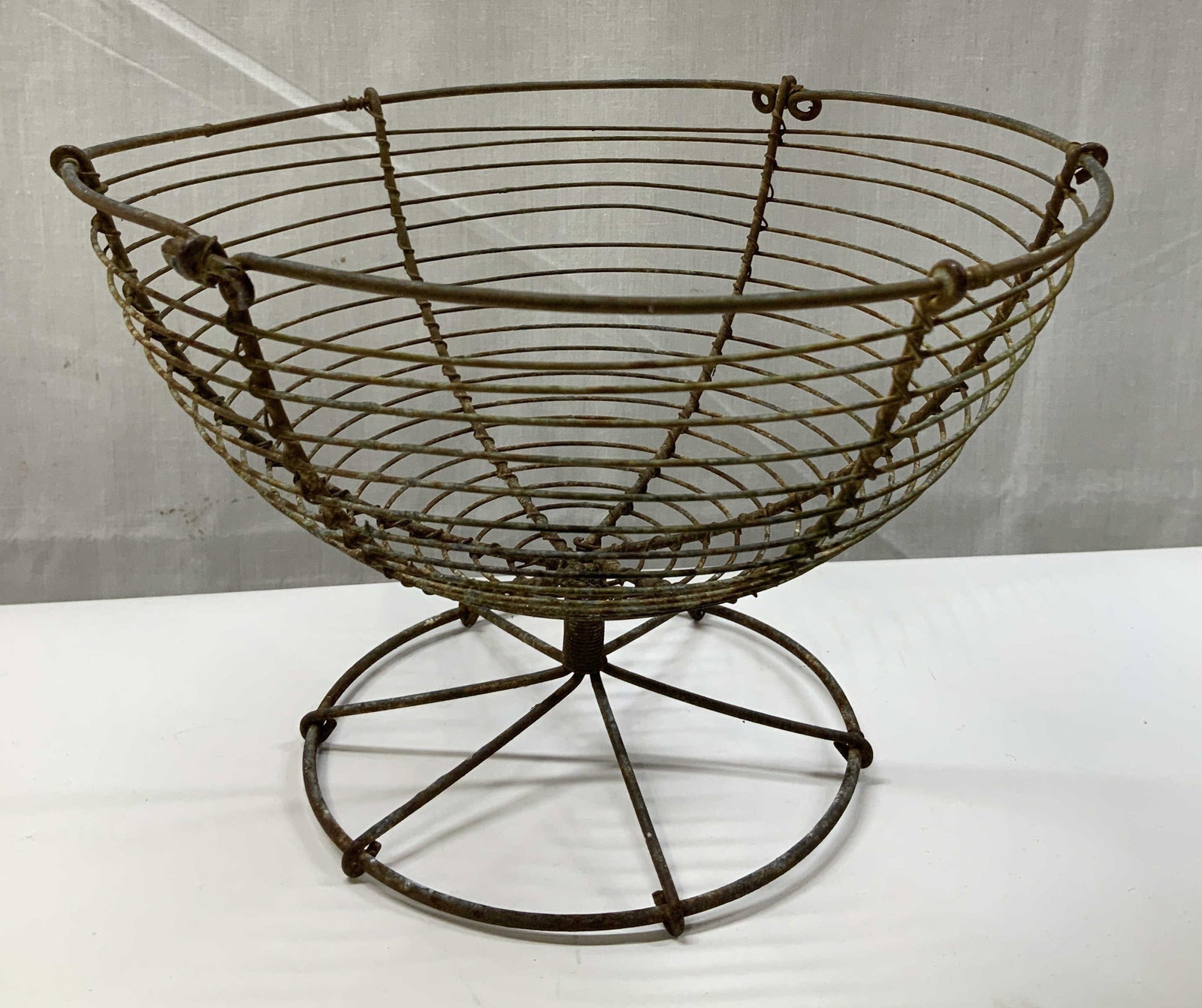 Antique Footed Wire Basket: Antique, possible vintage. Wire basket features a footed base. Open wire design. No visible signature or markings. Surface wear consistent to age, use & exposure. Measurements: length 8.5in x