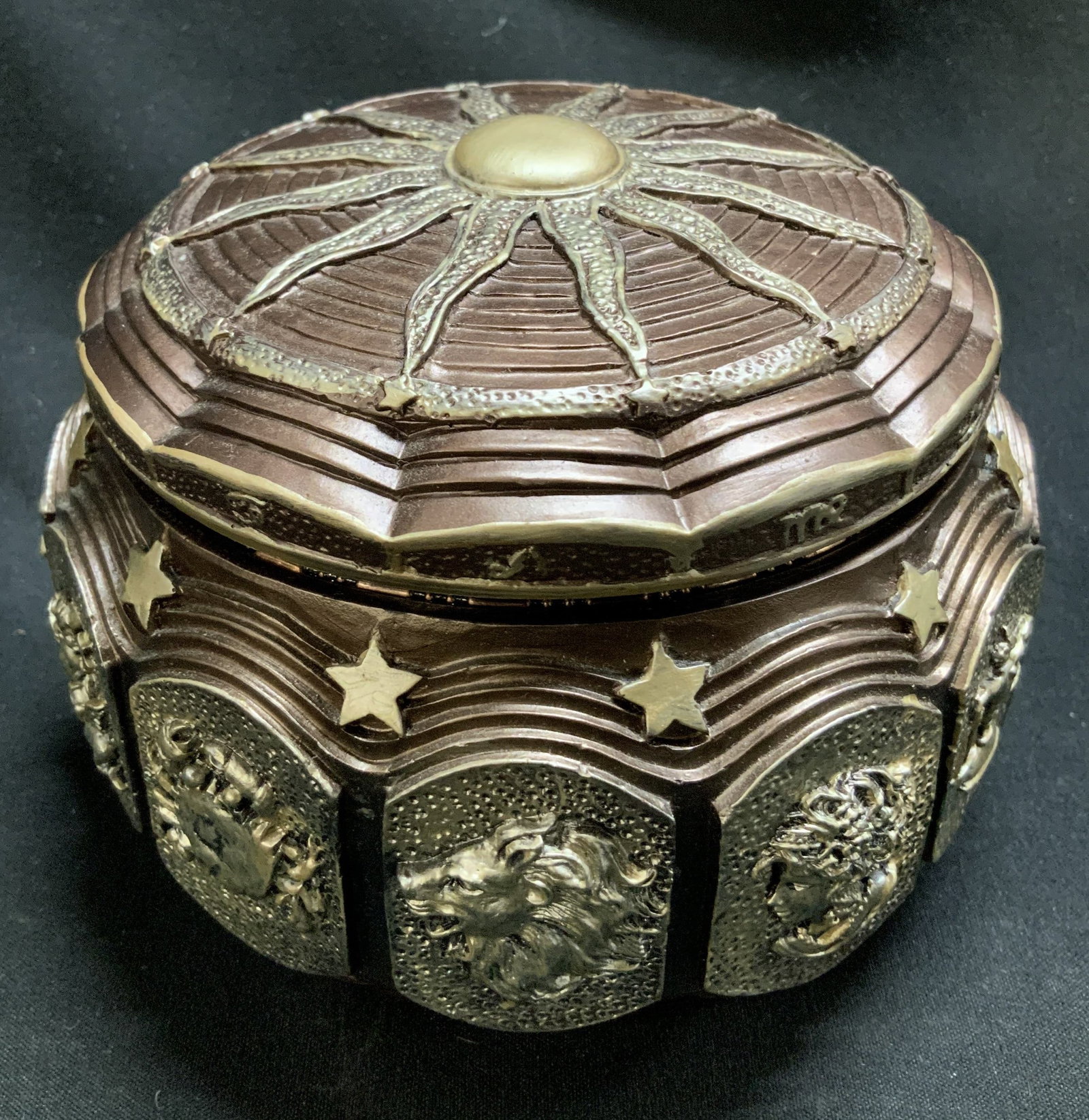 Sankyo Astrology Zodiac Musical Box: Sankyo musical box featuring zodiac signs on the exterior & blazing sun design on lid. Resin material. Plays music. Signed & marked on underside. Reads, SANKYO. Surface wear consistent to age, use & e