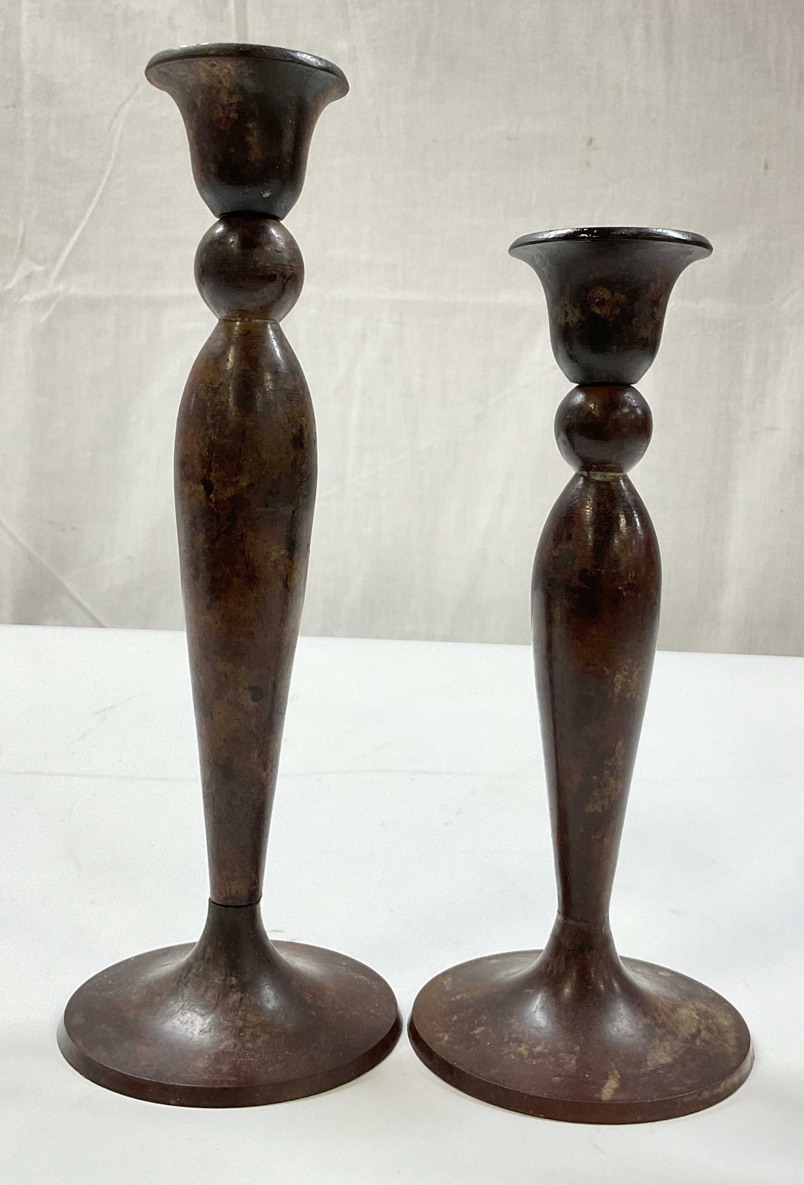 Near Pair Metal Taper Candle Holders India: Near pair of metal brown toned taper candle holders. Marked made in India on underside. Round flat base. Bulbous stem and flared rim. Brown aged patina. Largest measures ht approx 10 inches base diam