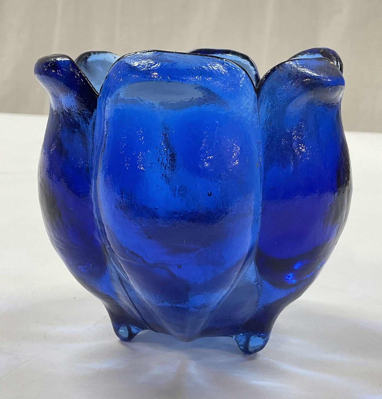 Cobalt Blue Tulip Footed Art Glass Candle Holder: Cobalt blue tulip footed art glass candle holder. Hand blown art glass. Three feet on underside. Tulip shaped, scalloped edges. Ribbed surface. Measures ht approx 4 inches diam approx 4 inches. Some s