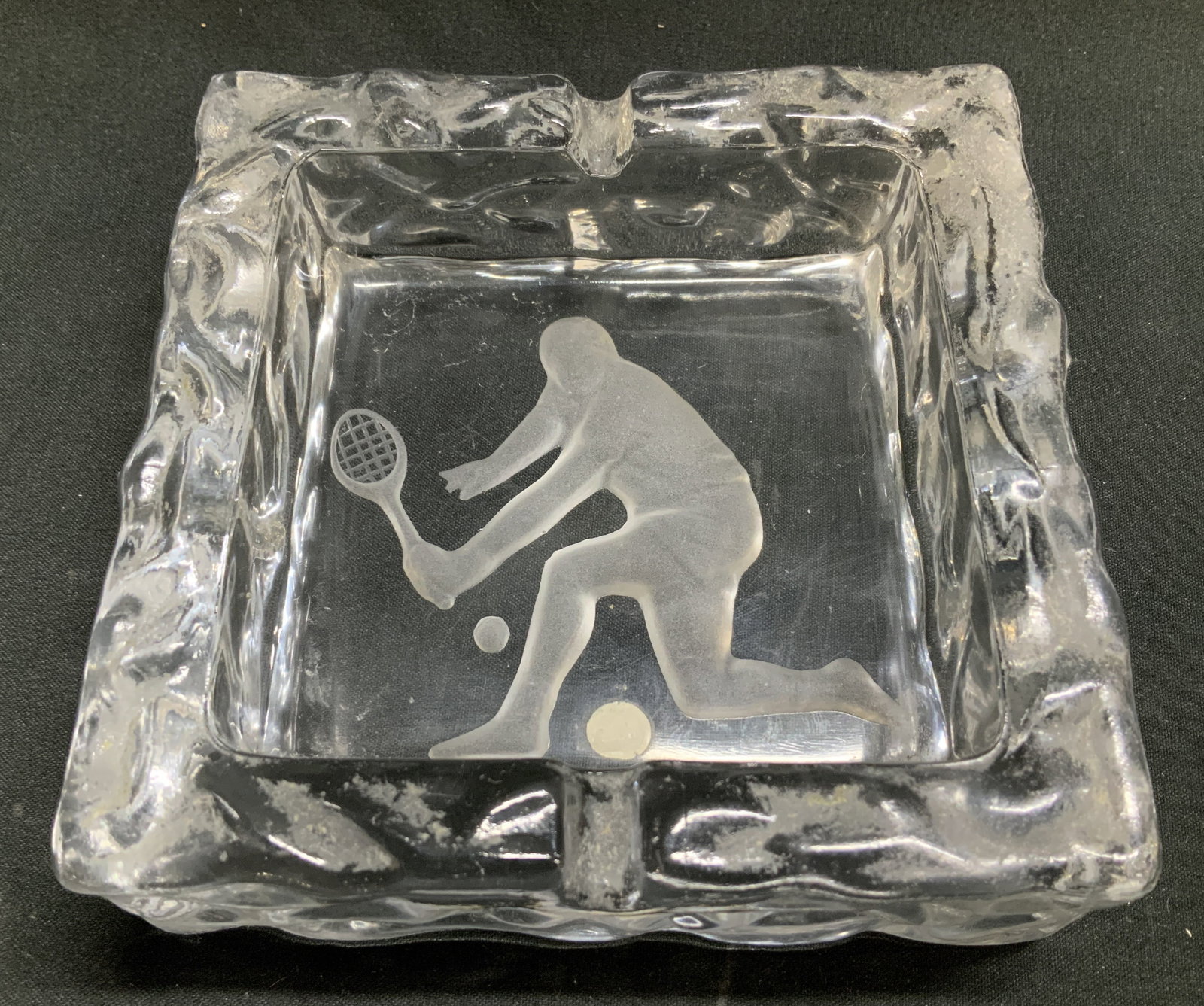Vtg Tennis Player Clear Glass Ashtray JAPAN: Vintage clear glass ashtray featuring an etched figure of a tennis player in center. Textured exterior. Signed & marked on underside. Reads, Japan. Surface wear consistent to age, use & exposure. Meas