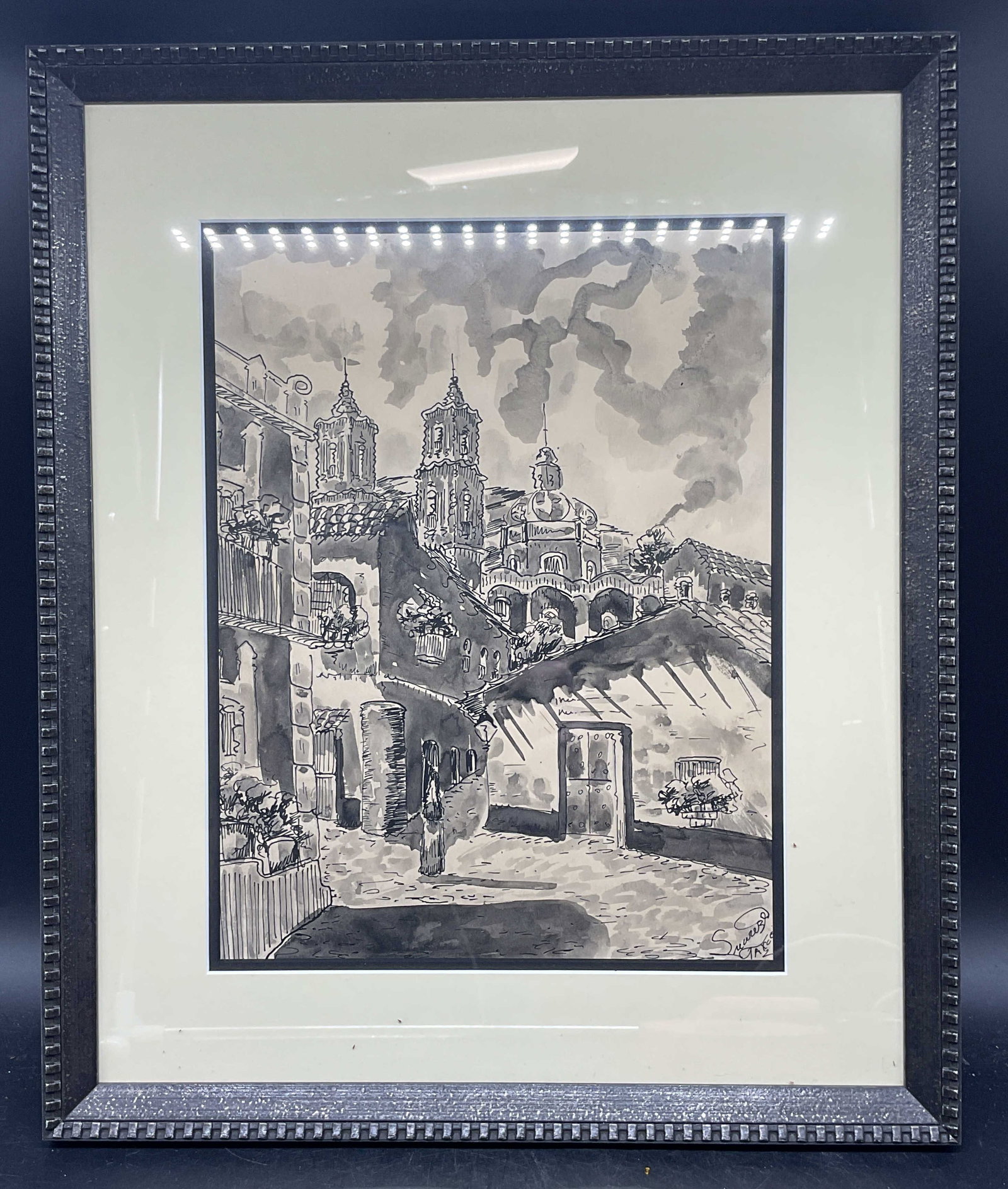 Signed Suarez Mexican Cityscape Ink Painting: Framed and matted ink painting. Signed lower right, Suarez, Taxco. Mexican scene with view of city. Black wood frame. Not examined out of frame. Frame measures approx. 18.5 x 15.5 inches. Some wear co