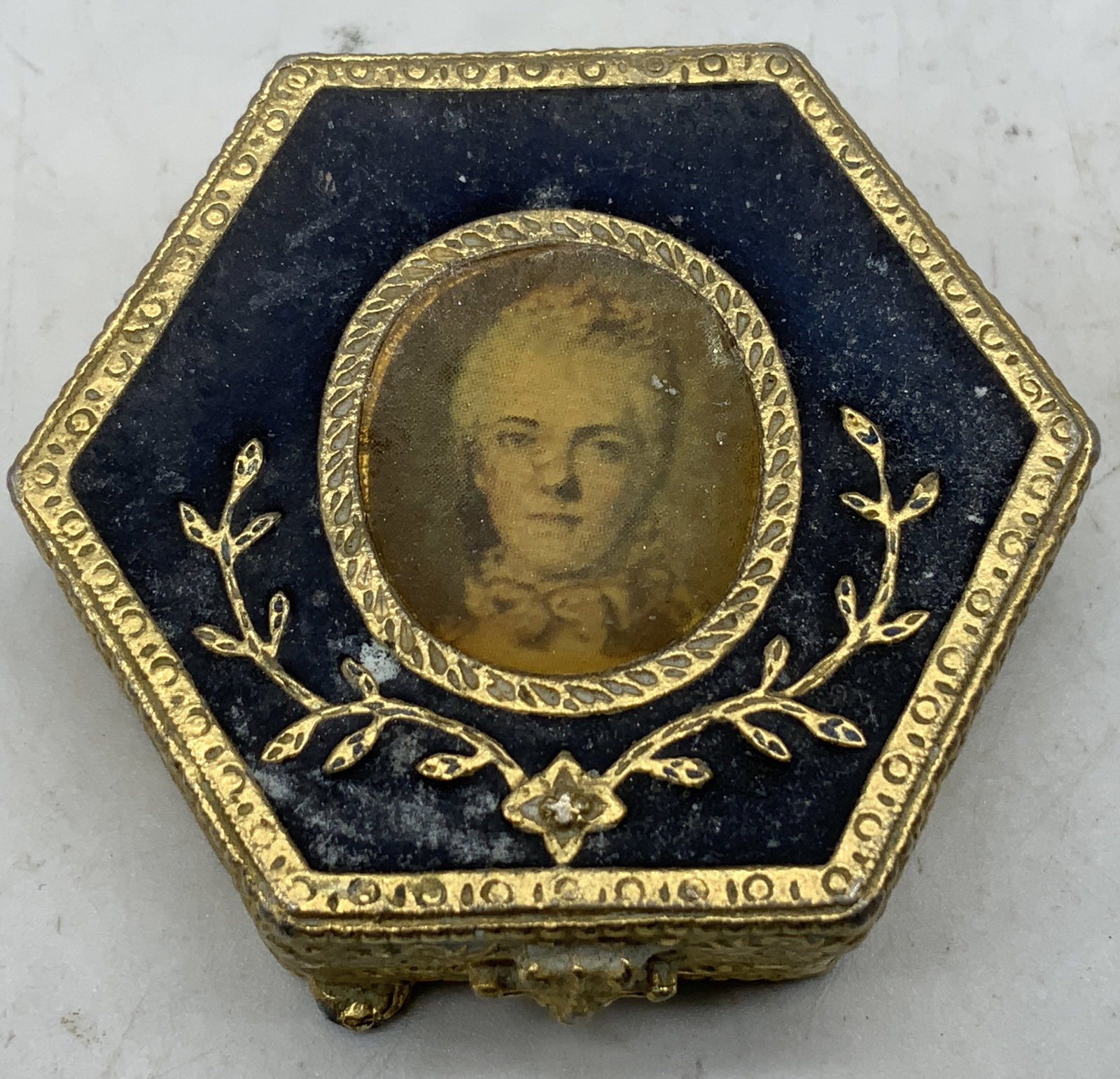 Vtg Estee Lauder Royal Enamel Powder Compact: Vintage Estee Lauder hexagonal featuring a dark blue enamel top with a portrait Marie Antoinette. Ornate detailing. Gilt metal. Surface wear consistent to age, use & exposure. Measurements: length 2in