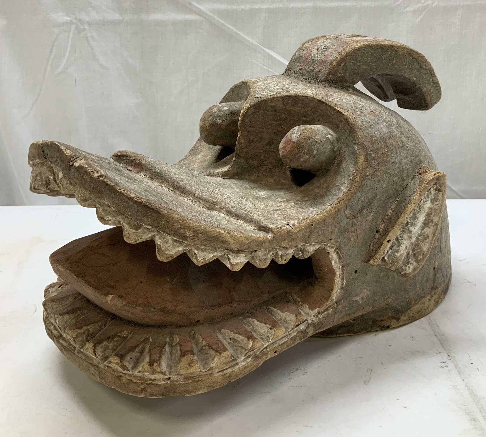 Vtg Carved Wooden Suaga Helmet Mask: Vintage wooden suaga helmet mask. Intricate carved detailing. Bulging eyes & teeth. Surface wear consistent to age, use & exposure. Measurements: length of underside 13.2in x width 7.2in x height 8in.