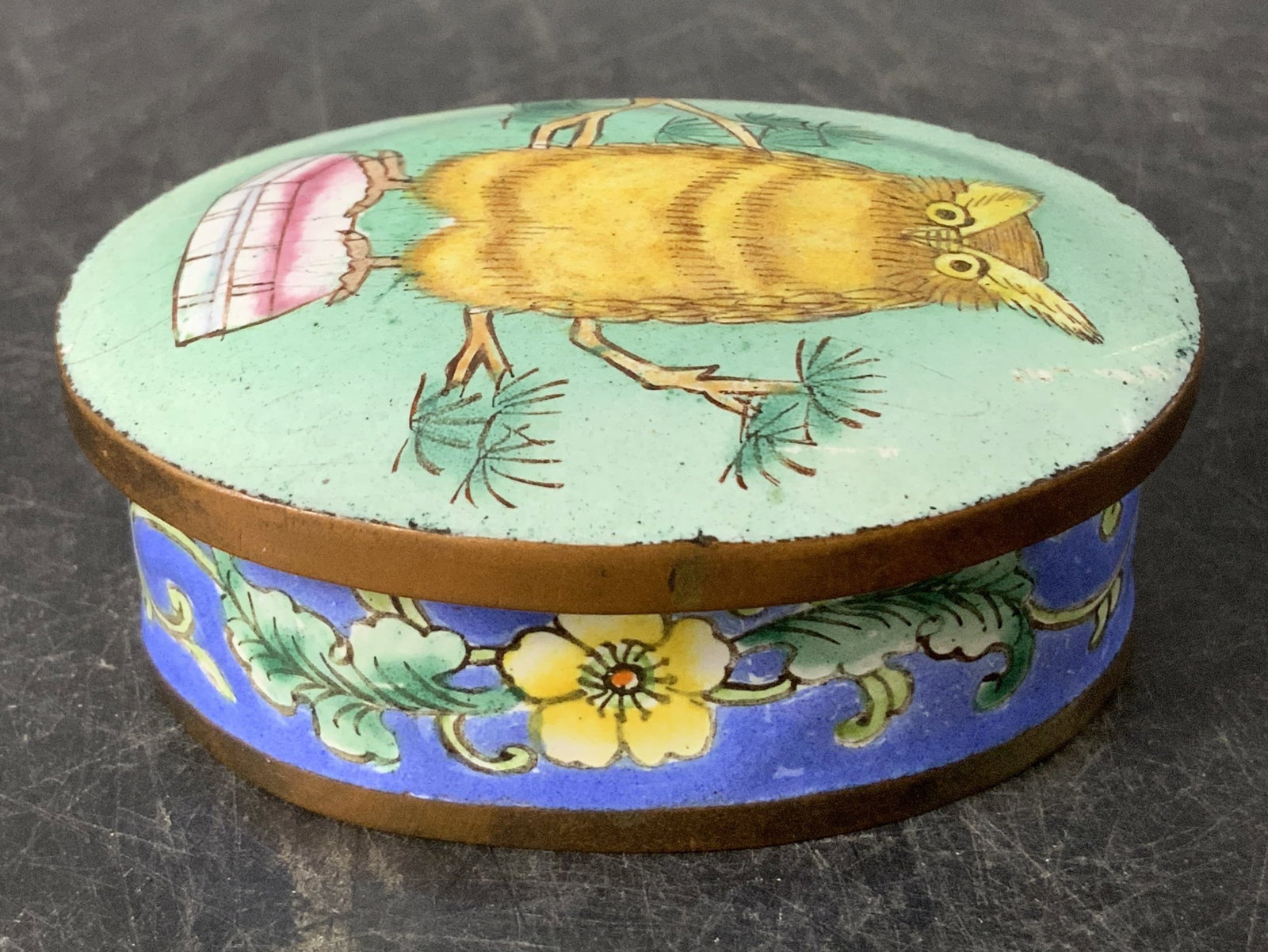 Knobler International Owl Enamel Trinket Box: Knobler International enamel trinket box features a hand painted owl with floral motifs. Green, yellow, pink, white & brown. Signed & marked on underside. Not legible, appears to read KNOBLER. Surface