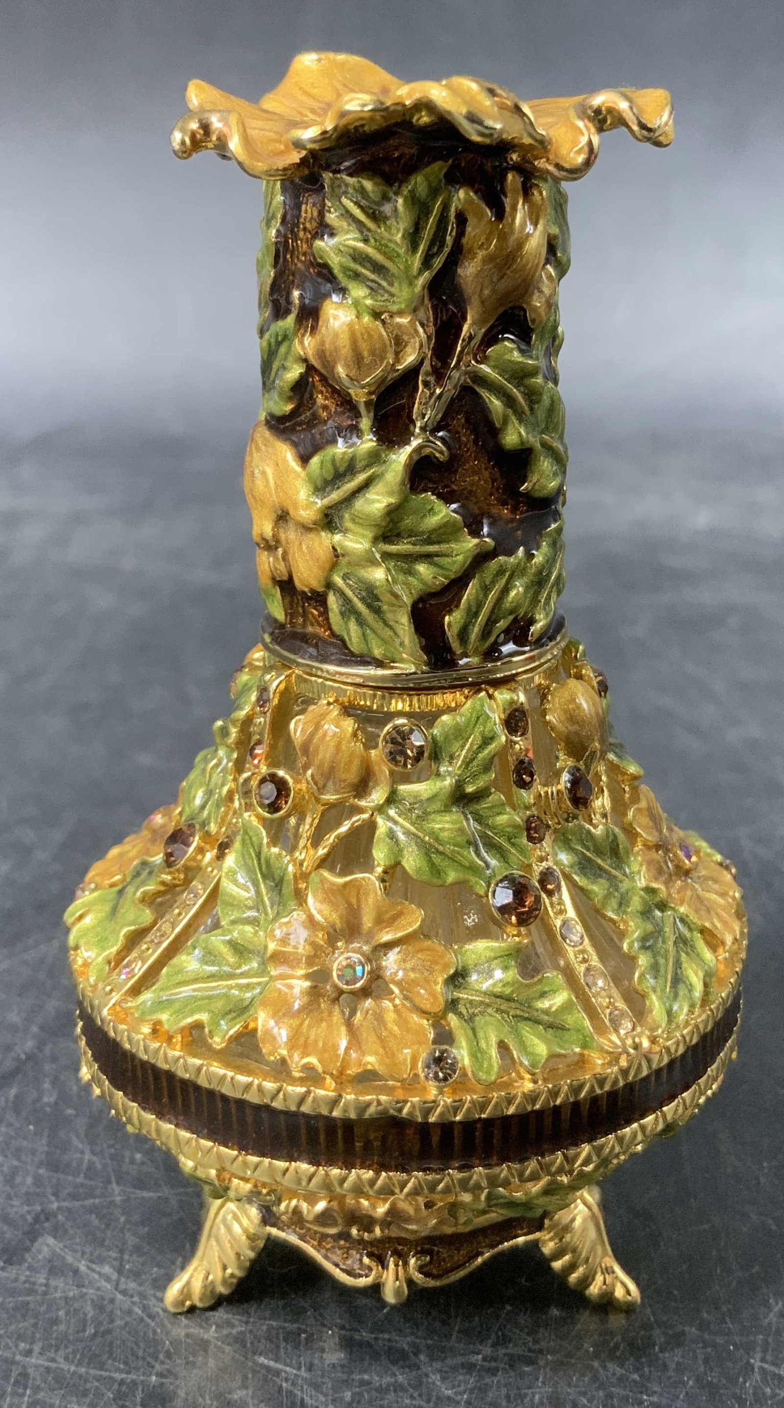 2004 Enamel & Rhinestone Perfume Bottle: 2004 perfume bottle featuring green & yellow enamel leaves. Rhinestone accents. Stands on 4 leaf like feet. Signed & marked on underside. Reads, 2004. Surface wear consistent to age, use & exposure. M