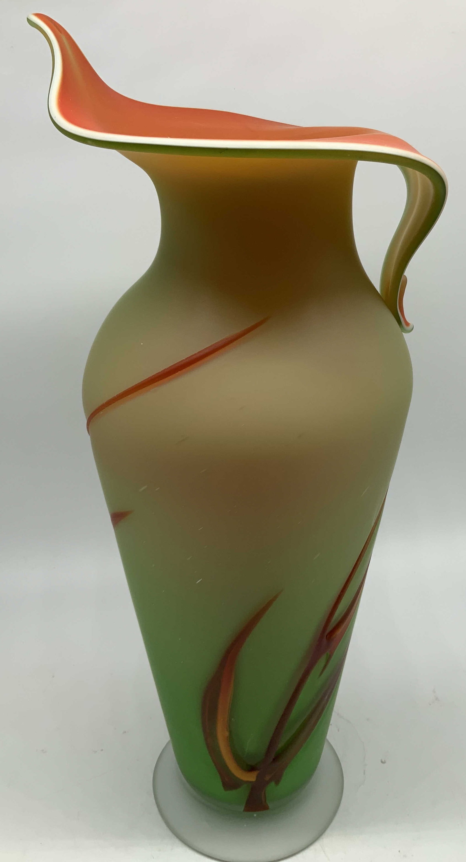 Sgnd Vtg Hand Blown Art Glass Vase: Vintage hand blown art glass vase with green, orange, white & red tones. Ruffled lip & handle. Round base. Surface wear consistent to age, use & exposure. Signed & marked on underside. Not legible. Me