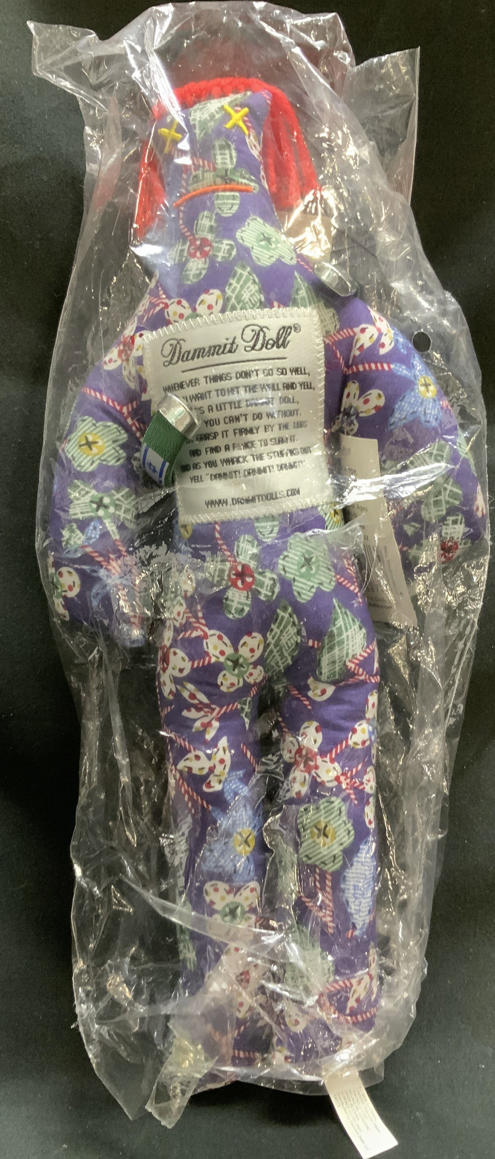 2013 Dammit Doll Floral Pattern NIP: 2013 Dammit Doll features a floral design on body. Red spaghetti like hair. New in plastic. Polyester fibers. Signed & marked. Reads, 2013 DAMMIT DOLLS. Surface wear consistent to age, use & exposure.