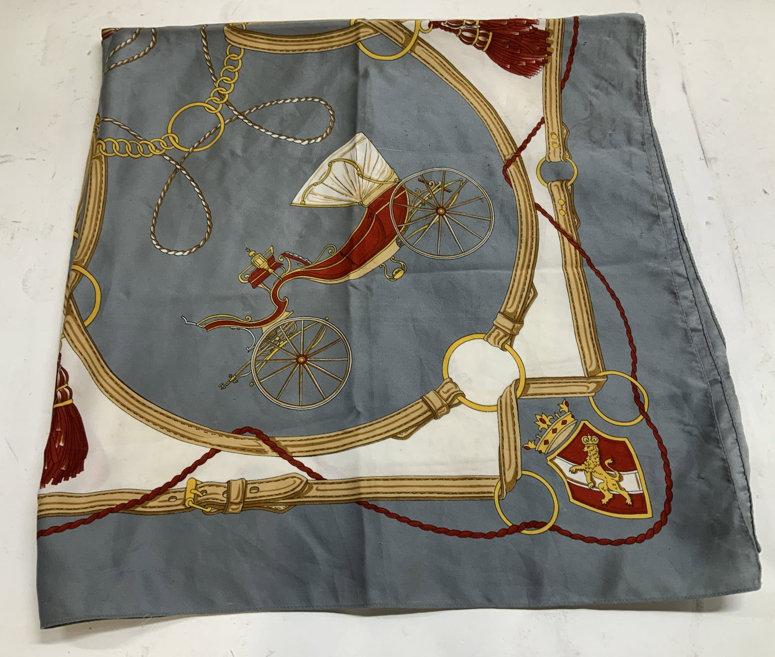 Vtg Grey & Red Equestrian Square Scarf: Vintage scarf is grey, red, yellow & white toned. Tassel, coat of arms & carriage motifs. Feels like synthetic. Surface wear consistent to age, use & exposure. Measurements: length 34in x 33.7. Vintag