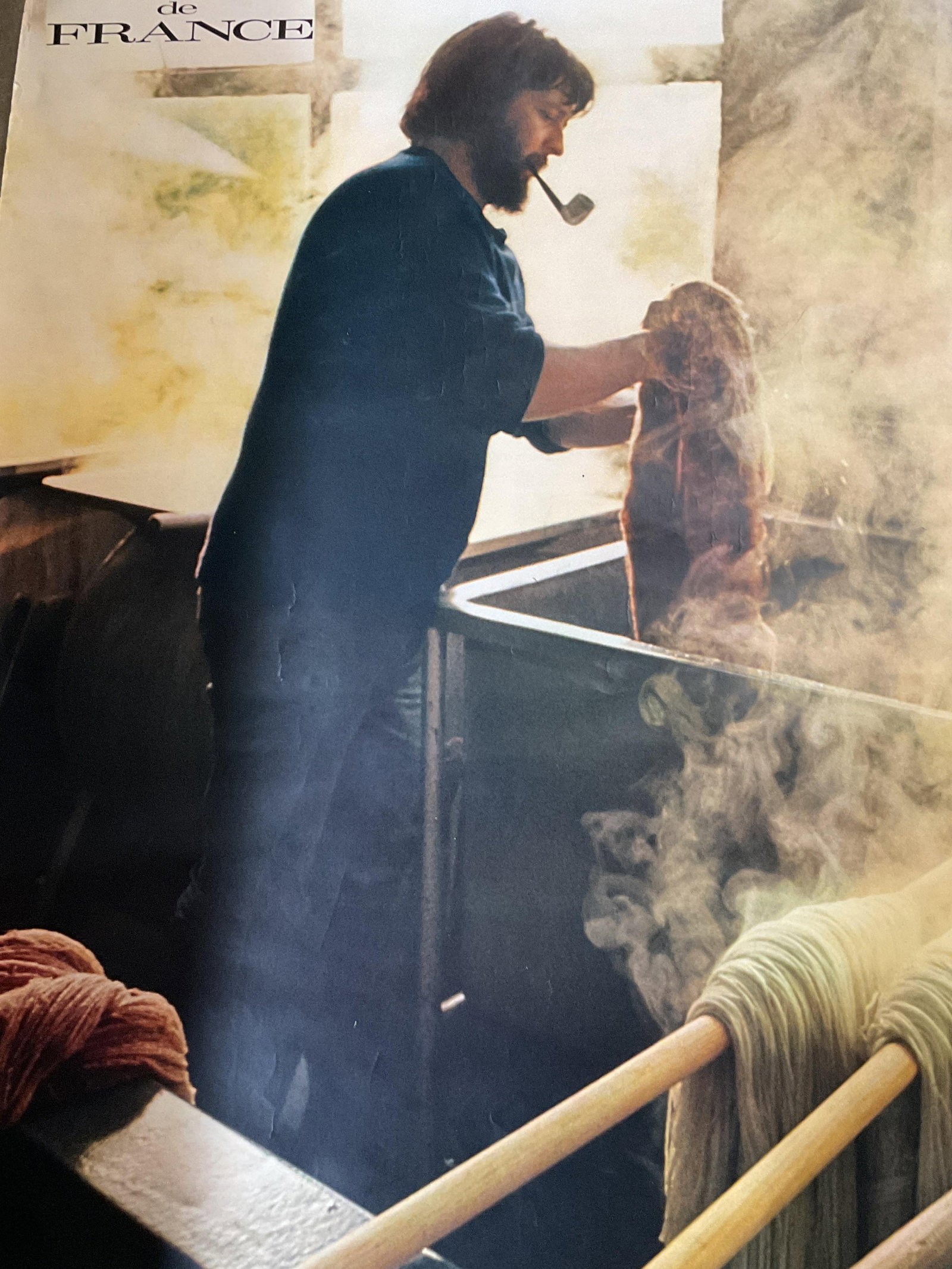 Artisans De France Promotional Tourism Poster 39in: Artisans De France promotional tourism poster. Published by and for the French government. Printed in France. Features a male figure smoking a pipe while dyeing materials. More inscriptions as photogr