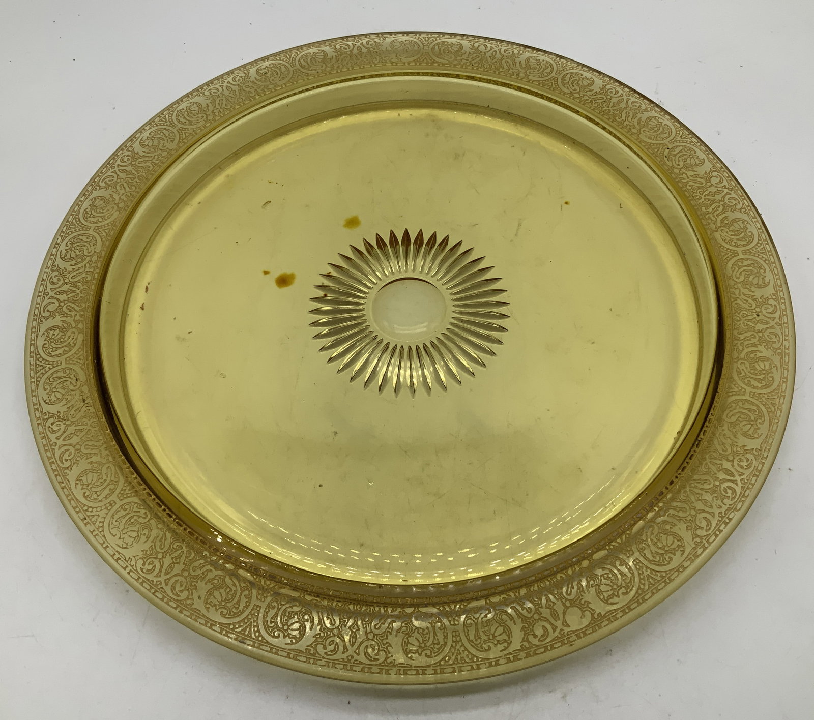 Vtg Amber Glass & Gilt Round Serving Tray: Vintage amber glass round serving tray featuring gilt scroll motifs on rim. Sunburst style in center. Surface wear consistent to age, use & exposure. Measurements: length 11.5in x width 11.5in. Vintag