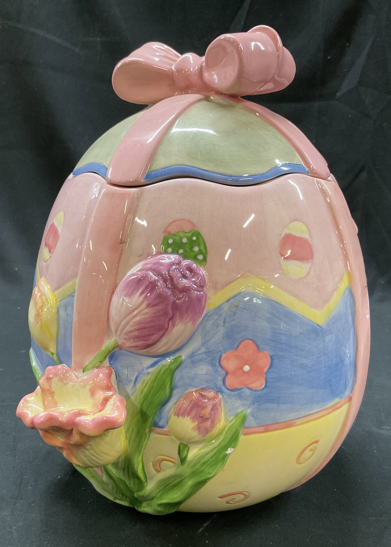 Davids Cookies Ceramic Egg Cookie Jar: Davids Cookies ceramic egg shaped lidded cookie jar. Marked Davids Cookies on underside. Egg shaped jar. Applied floral and bow motifs. Hand painted egg motifs. Varying colors. Scalloped edge. Glossy 