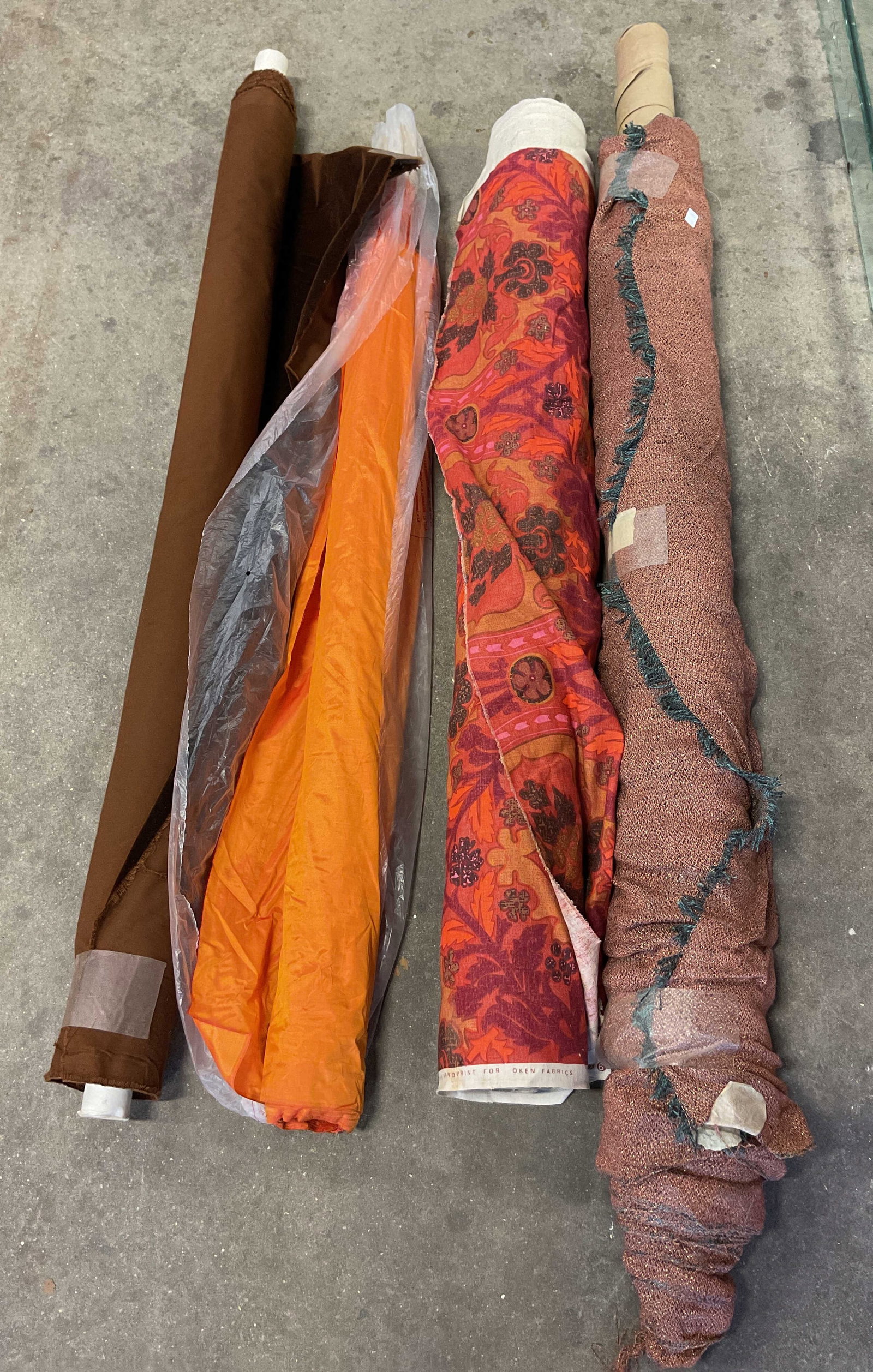 Lot 4 Designer Floral & Solid Print Fabric Bolts: Lot of 4 designer fabric bolts. Mix materials. Silk, velvet, linen and more. Floral prints. Orange, pink, and brown. Fringed trim. Brand includes Oken Fabrics. Not Measured, Unrolled, or Inspected. So