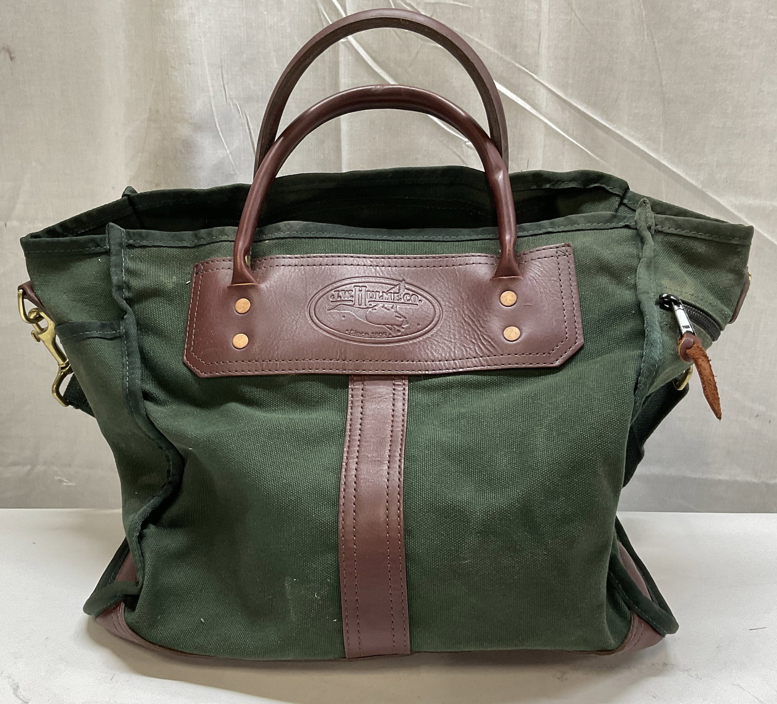 J.W. Hulme Co. Canvas & Leather-Style Bag: J.W. Hulme Co. Green Canvas & Brown Leather-Style Bag. Monogrammed on The Back for Malaby Bradley Attorneys at Law. Condition Consistent with Exposure. Measures app 13.5in H x 14.5in L. J.W. Hulme Co,