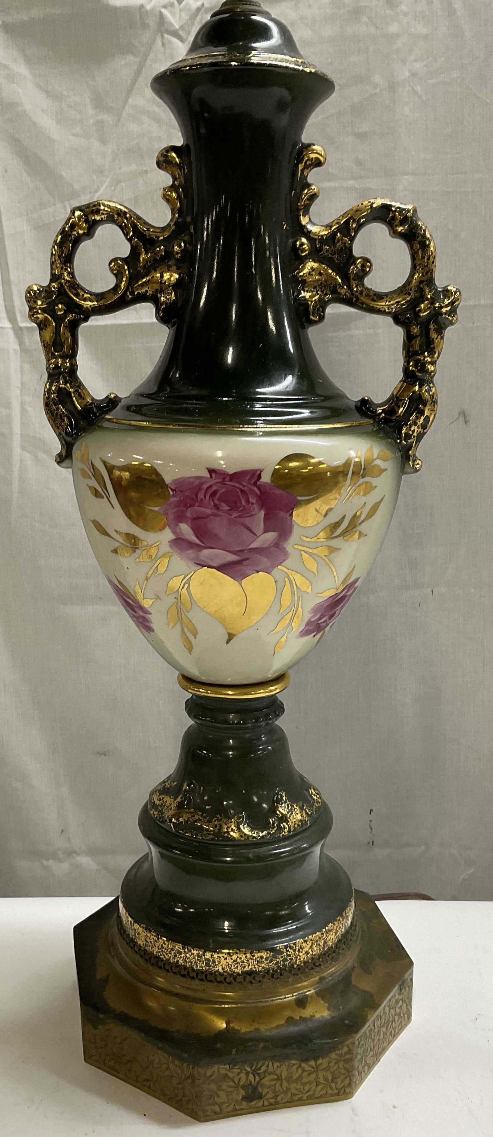 VTG Porcelain Painted Rose Urn Shaped 34in Lamp: Vintage Green Porcelain & Painted Rose Urn Shaped Table Lamp. Gilt Accents. Rests on an Octagonal Brass Finish Metal Stand with Foliage Design. Some Aging to Metal Consistent with Exposure. Has Not Be