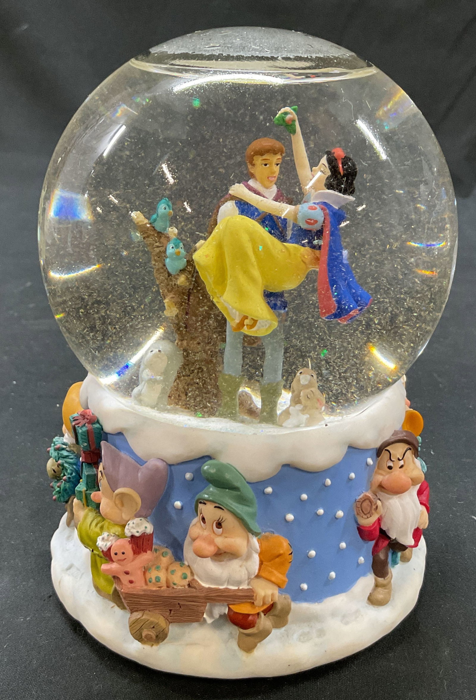 Enesco Disney Snow White Musical Snow Globe: Enesco Disney Snow White musical snow globe. Marked on underside as photographed here. Glass globe and resin base. Base features the seven dwarfs. Prince Charming and Snow White are inside the globe. 