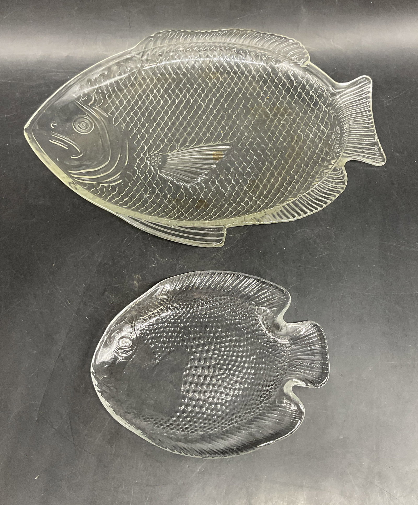 Lot 2 Clear Glass Fish Dishes: Lot of 2 pieces. Clear glass fish motif dishes. Larger measures approx. 11 x 8 inches. Some scratching. Fish dish, fish platter, glass dish, home decor, home accessories, table decor, table accessorie