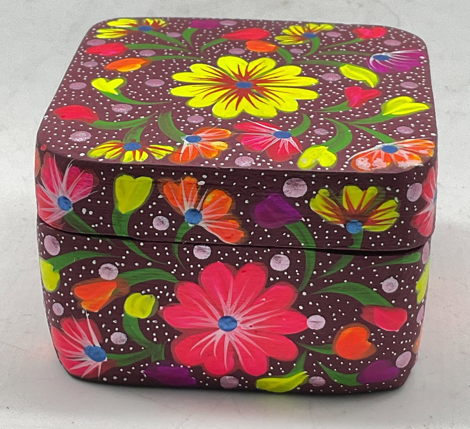 Vintage Hand Painted Wood Trinket Box: Vintage hand painted wood hinged trinket box. Square shaped box. Hinged lid. Hand painted purple background. Painted floral motifs in varying colors. Measures approx 3.5 x 3.5 x 2.5 inches. Some scrat