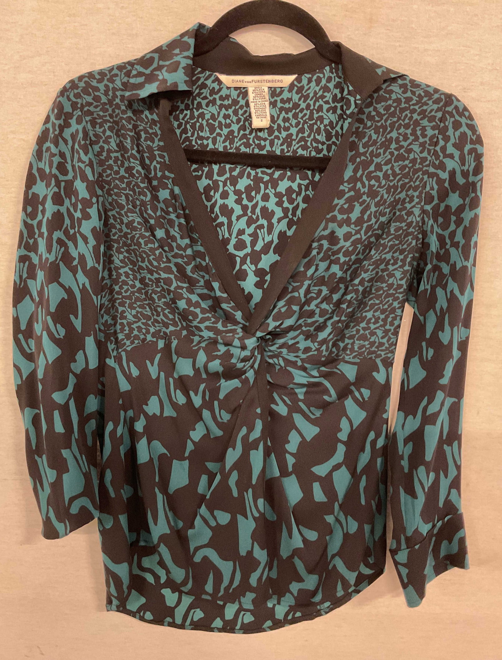 Diane Von Furstenberg Blue & Black Blouse: Diane Von Furstenberg blue and black blouse. Size 2. Silk material. Collared and long sleeves. Twist design. Geometric pattern in blue and black. Front button. Wear consistent with exposure. Blouse, s