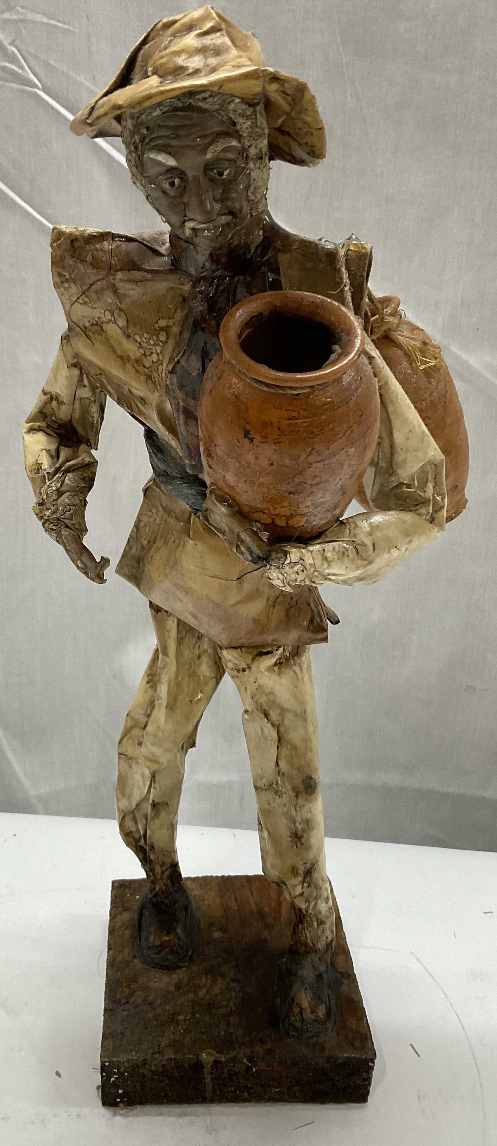VTG Mexican Folk Art Paper Mache Figurine: Vintage Mexican Folk Art Paper Mache Figurine. Depicts a Street Seller Holding Pottery Vases. Wooden Base. Condition Consistent with Exposure. Measures app 13.5in H x 4in L. Vintage Figurine, Mexican
