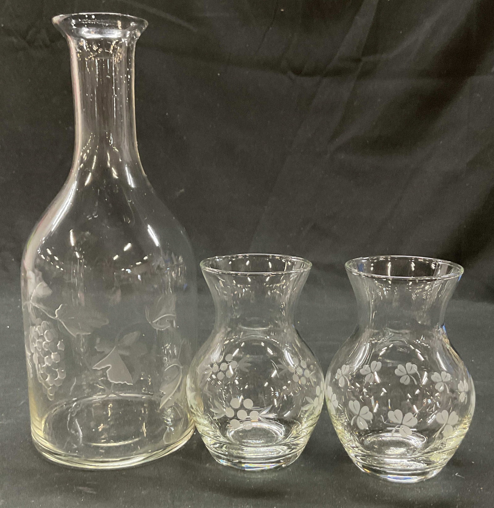 Lot 3 Etched Glass Grapevine Decanter & Bud Vases: Lot of 3 items. Etched glass grapevine decanter. Bulbous body with slender neck and wide rim. Does not include stopper. Etched grapevine motif. Lot also includes two etched glass bud vases. Bulbous bo