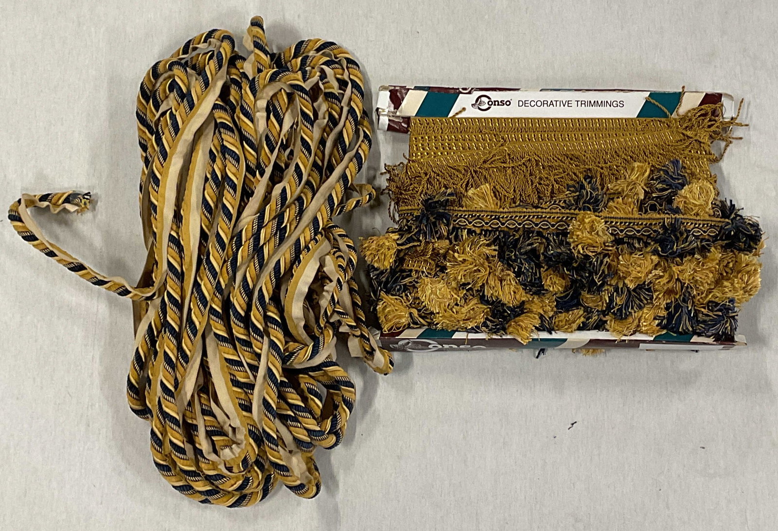 Group Lot Gold & Blue Woven Fabric Trims: Group lot of mixed woven, tassel, and twisted fabric trims in gold and blue. Not Measured, unfolded, or otherwise inspected. Yardage unknown. Sold As Is. May contain some tears or blemishes. Part of L