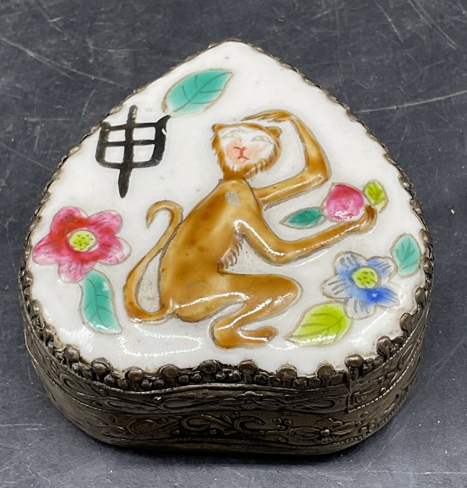 Vtg Porcelain Monkey Trinket Jewelry Box: Vintsge Chinese style silver tone and porcelain heart shaped trinket or jewelry box with interior mirror. Hand painted monkey and flower design. Measures approx. 2.5 x 2.25 x 1 inches. Wear including 