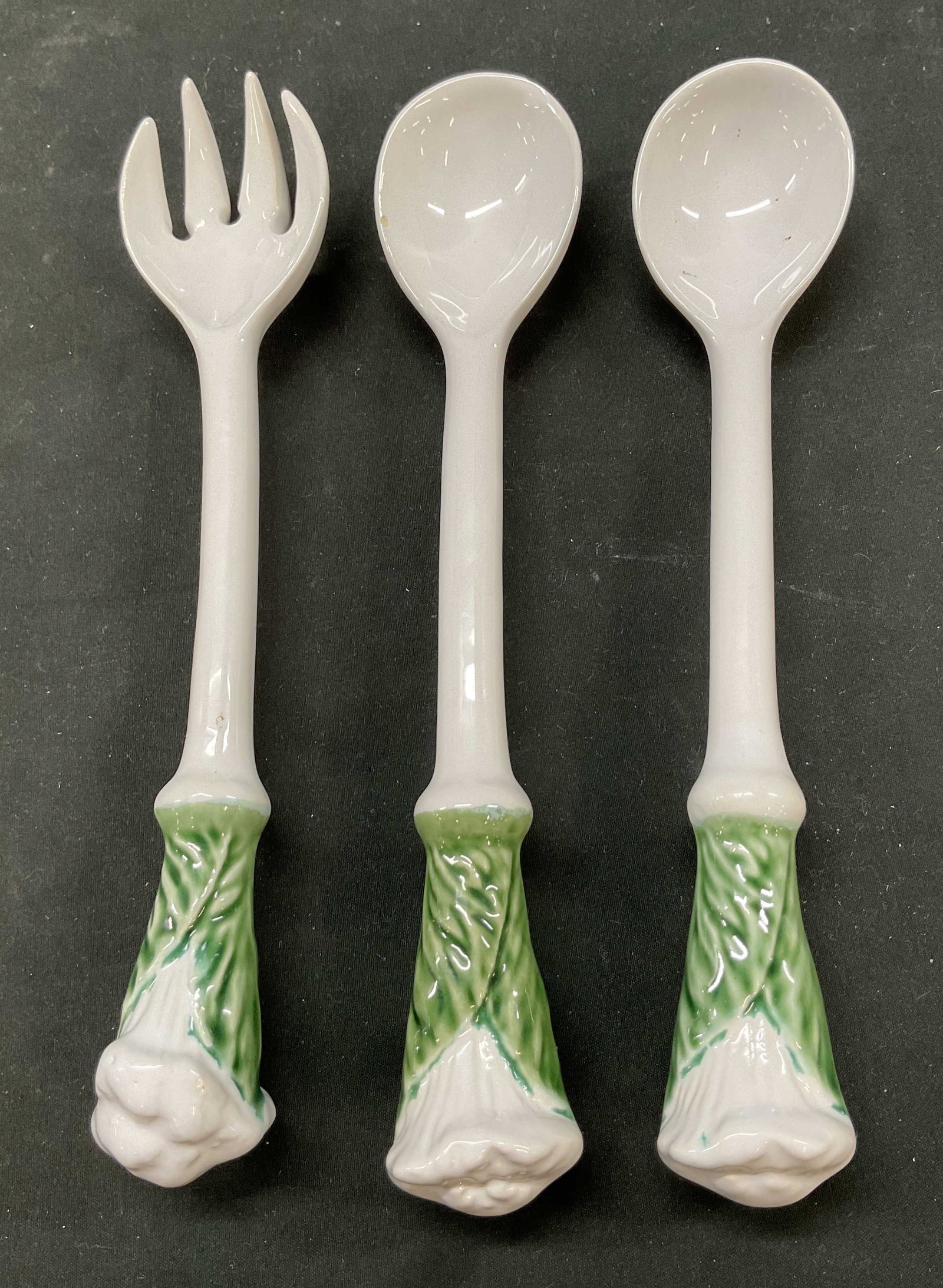 Lot 3 Vintage Ceramic Leaf Serveware: Lot of 3 items. Vintage ceramic leaf serveware. Includes two serving spoons and one serving fork. Handles have leaf motif design hand painted green. Largest measures approx 9 inches long. Some crazing