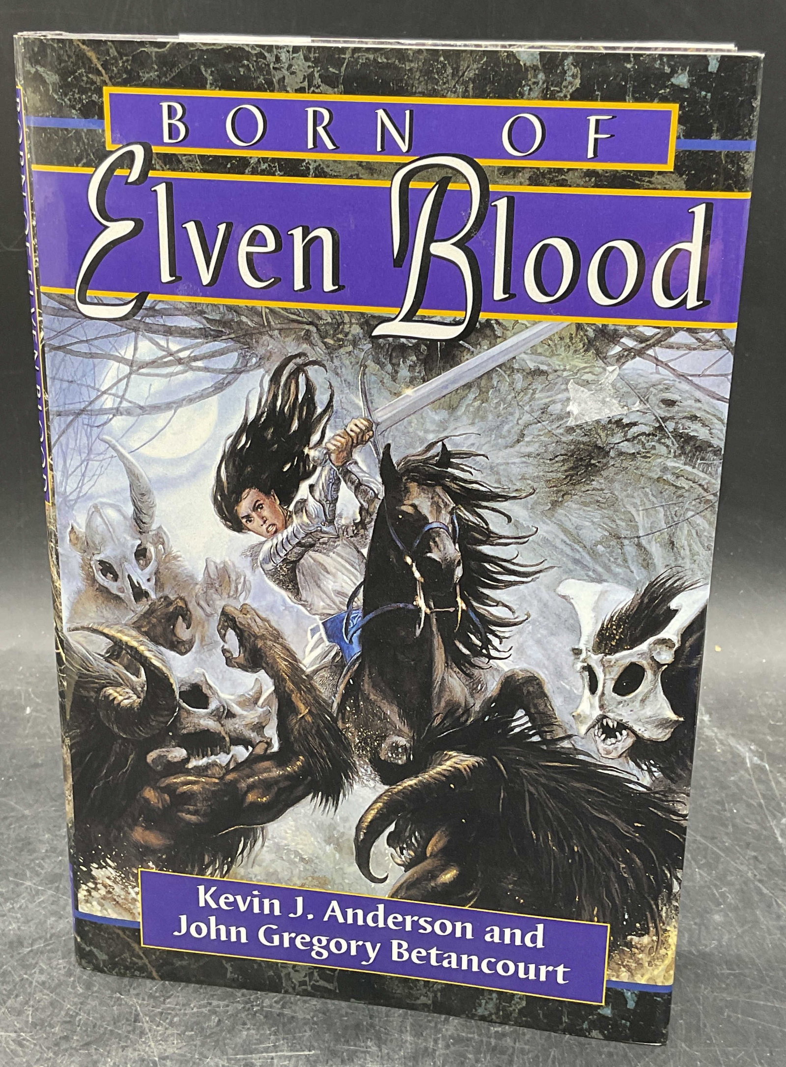 1995 Anderson Betancourt Elven Blood 1st Edt: Hardcover first edition copy of Born of Elven Blood by Kevin J Anderson and John Gregory Betancourt. Atheneum, 1995. Illustrated. Measures approx 9.25 x 6.25 inches. Some wear to cover, pages, and bin