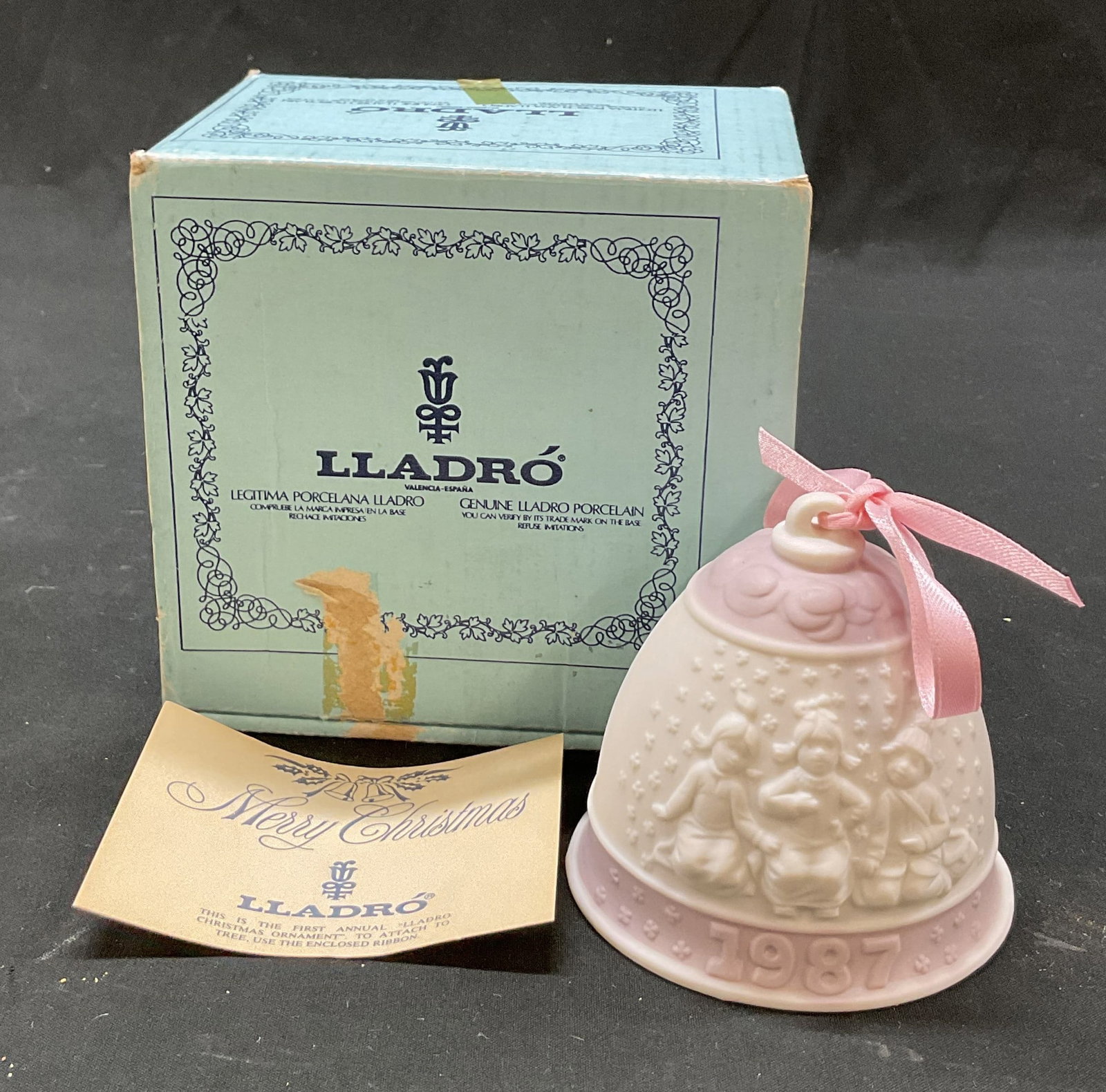 1987 Lladro Porc Xmas Bell Ornament Spain W Box: 1987 Lladro First Annual porcelain Christmas bell ornament. Marked on underside, made in Spain. Comes in original box. Bell ornament in white and pink. Features imagery of children playing in the snow